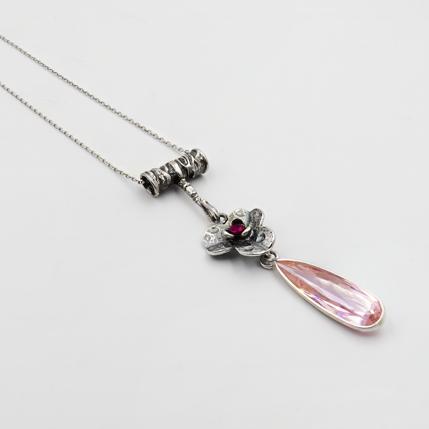 תליון כסף רומנטי בעבודת יד, עם עיטורי פרח בסגנון אלגנטי ונגיעה של אבן ורודה בגוון בורדו במרכזו. האלמנט המרכזי מתכתב עם טבע, פריחה עדינה ונשיות עוצמתית. מתחתיו משתלשלת טיפה ארוכה בגוון ורדרד שקוף – אבן נוצצת בגימור מושלם שמוסיפה תחושת קלילות וזרימה. השרשרת כולה משדרת אופי אמנותי וייחוד, מתאימה למי שאוהבת תכשיטים שאומרים משהו על מי שלובשת אותם. פריט מושלם להוסיף נגיעה של קסם אישי להופעה.

