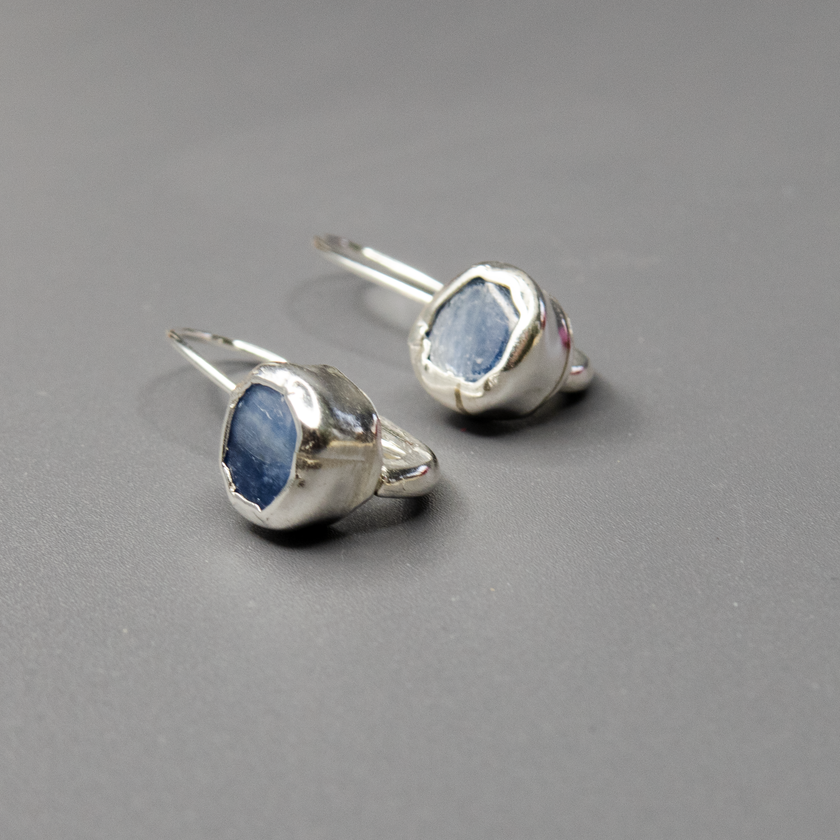 עגילים בעבודת יד עם אבני קיאנייט בגוון כחול שקוף-עמוק, המחוברות למסגרת כסף עדינה. שילוב בין עיצוב נקי לחומר גלם עוצמתי וטבעי. האבנים מוסיפות תחושת זרימה ושלווה, והכסף מדגיש את היופי של האבן. מתנה אידיאלית לאישה שמחפשת חיבור בין יופי לטבע.

