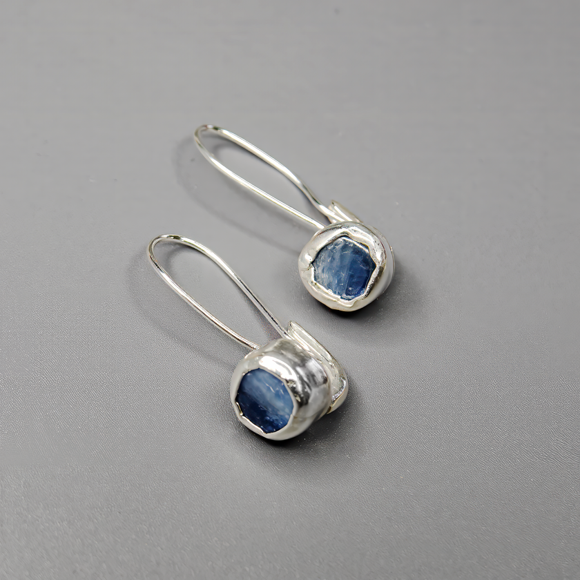 עגילי כסף אלגנטיים עם קיאנייט טבעי – תכשיט בעבודת יד שמשלב בין חוסן ועדינות. האבן הכחולה יוצרת מראה ייחודי ואישי, ומתאימה למי שאוהבת צבעים עמוקים עם נוכחות שקטה. עגילים קלילים ונוחים ללבישה, שמוסיפים ברק כחול עמוק לכל הופעה.

