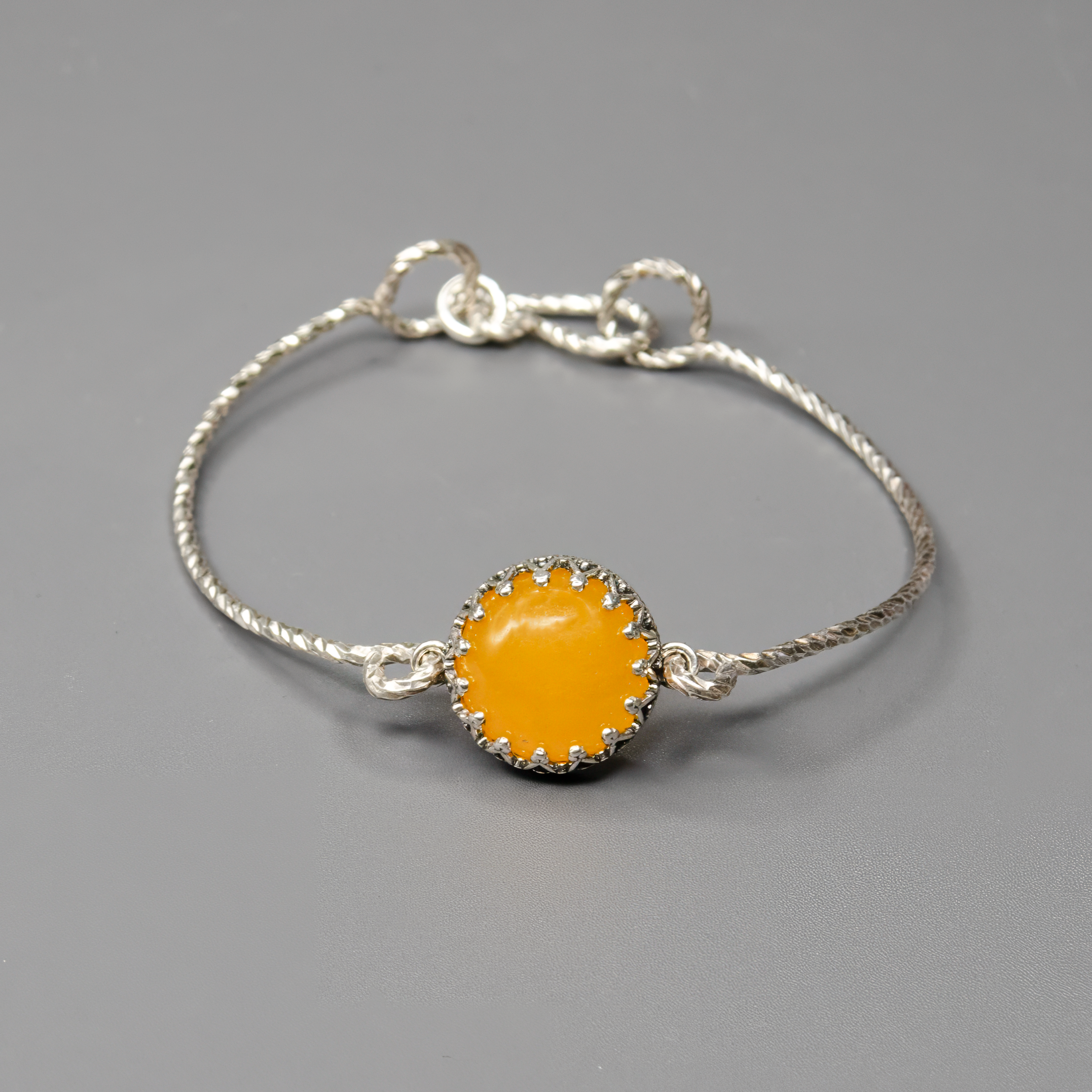 צמיד קשיח מכסף סטרלינג 925 בעבודת יד, משובץ באגת צהובה בגוון חמימה ובהיר. העיצוב הנקי מאפשר לאבן להיות במרכז הבמה – צבעה משתלב נפלא עם עור בהיר או כהה ומאיר את הלוק כולו. תכשיט שמחבר בין פשטות לרעננות, מתאים ליום יום, לאירועים או כמתנה עם אנרגיה חיובית. מושלם לנשים שאוהבות שילוב של טבע וסטייל.

