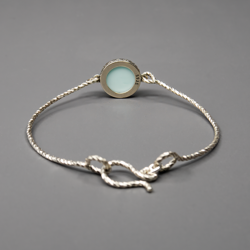 צמיד כסף בעיצוב קשיח עם שיבוץ של אופליט לבן-תכלת – אבן סינתטית ייחודית המשלבת מראה חלבי עם רמיזות קלות של כחול שמיים. האבן יוצרת מראה רגוע, טהור וקסום, שמתאים לסגנון בוהו מודרני או עיצוב רומנטי מינימליסטי. הצמיד מתאים במיוחד לכלה, לשושבינה, או למתנה עם משמעות. תכשיט על-זמני שניתן לשלב עם תכשיטים נוספים או לענוד לבד כמוקד עדין של תשומת לב.

