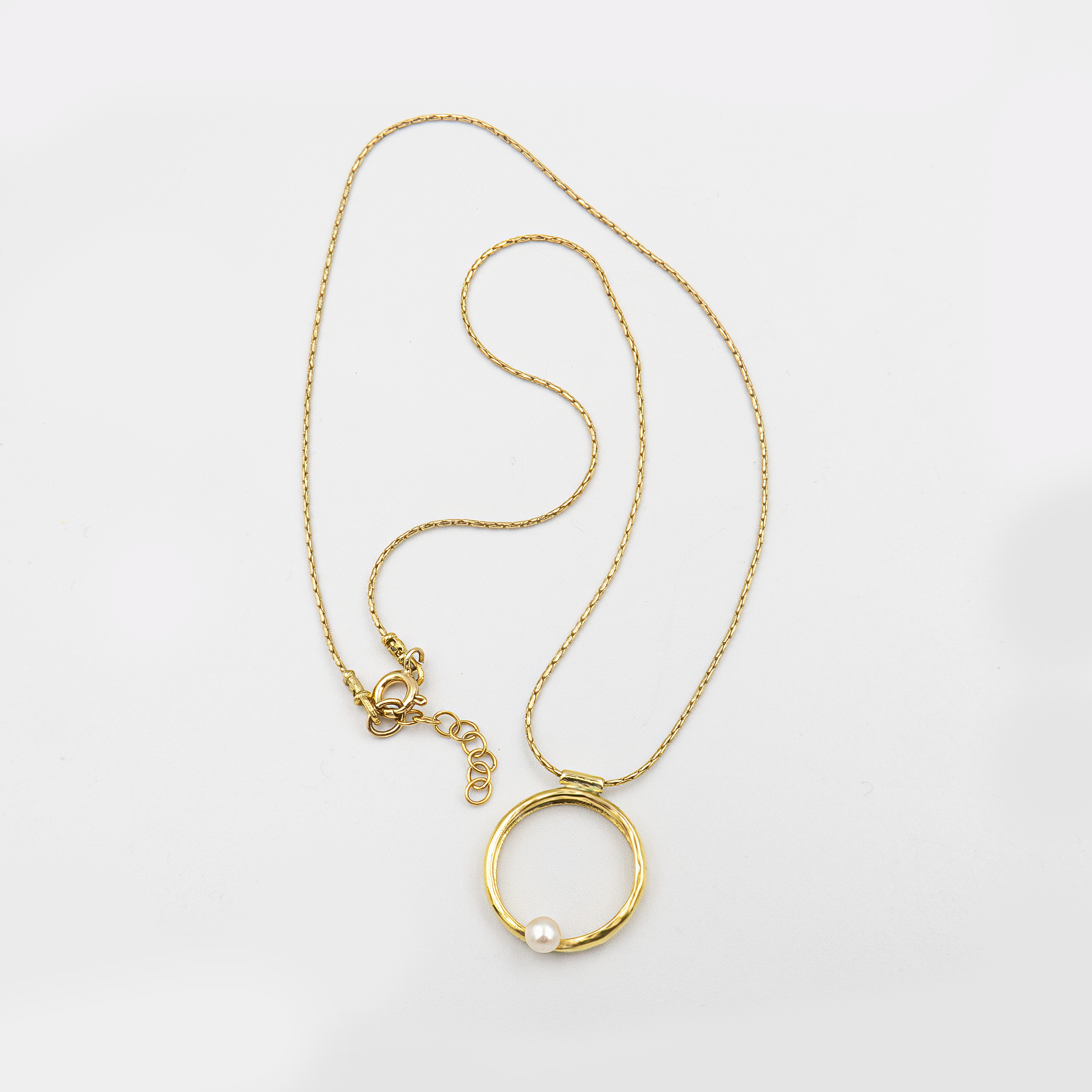 שרשרת בעיצוב אלגנטי עם אלמנט מרכזי מצופה זהב מבריק, המשובץ בפנינה זוהרת בגימור חלק – תכשיט קלאסי בעל נוכחות בולטת. הפנינה ממוקמת במרכז התליון ומקרינה אור רך וטבעי, תוך יצירת ניגוד מחמיא עם הציפוי הזהוב. עיצוב השרשרת משלב בין עיצוב על־זמני עם טוויסט עדכני, ומתאים לאירועים חגיגיים כמו גם ללבוש יומיומי עם נגיעה נשית. פנינים ידועות כמזוהות עם סטייל נשי טהור – ויחד עם הזהב, נוצרת הרמוניה מושלמת בין אלגנטיות לחמימות.