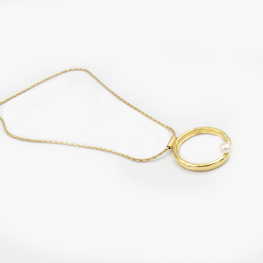 שרשרת בעיצוב אלגנטי עם תליון מוזהב בגודל דומיננטי, המשובץ בפנינת שמנת מעודנת – תכשיט קלאסי בעל נוכחות בולטת. הפנינה ממוקמת במרכז התליון ומקרינה אור רך וטבעי, תוך יצירת ניגוד מחמיא עם הציפוי הזהוב. עיצוב השרשרת משלב בין עידון נשי עם נגיעה עכשווית, ומתאים לאירועים חגיגיים כמו גם ללבוש יומיומי עם נגיעה נשית. פנינים ידועות כמשדרות תחושת רוגע ואלגנטיות – ויחד עם הזהב, נוצרת הרמוניה מושלמת בין אלגנטיות לחמימות.