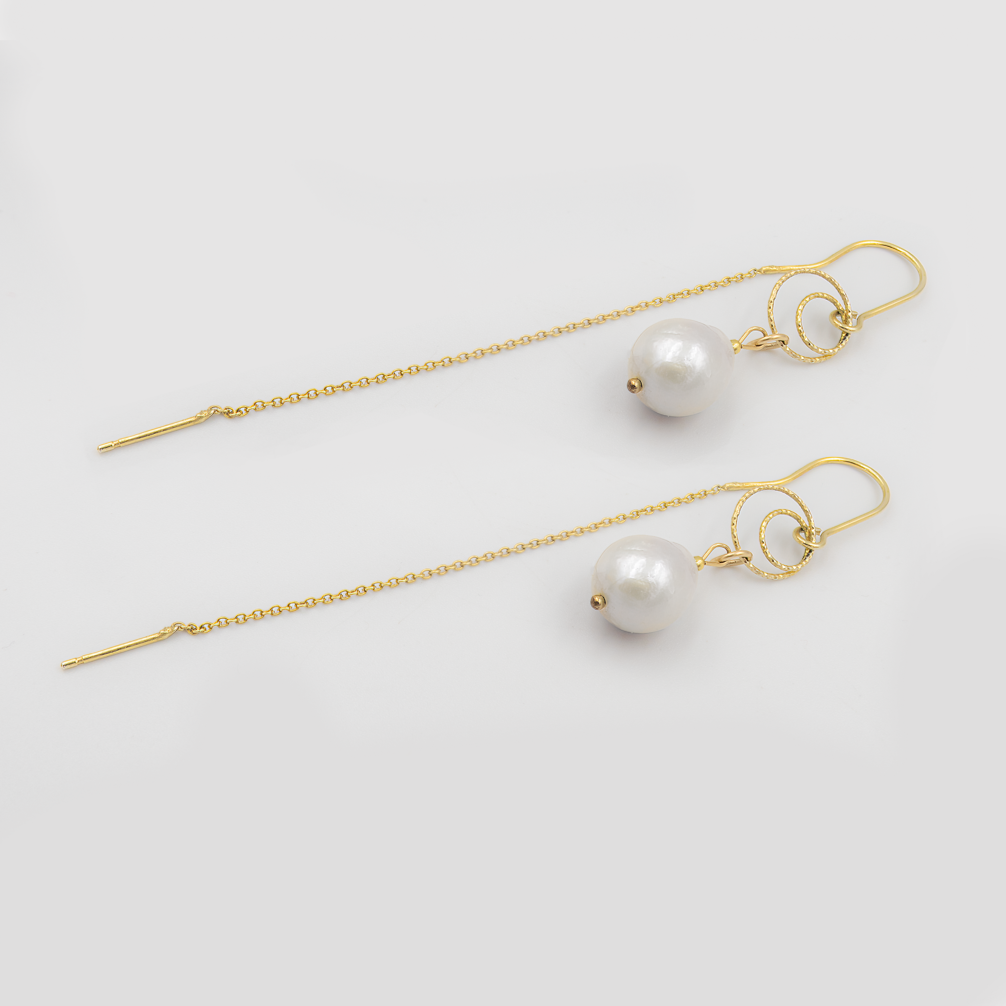 עגילי שרשרת אלגנטיים בעבודת יד עם פנינה לבנה עגולה ועדינה. תכשיט על-זמני עם נוכחות רכה ומרשימה שמתאים לרגעים הכי משמעותיים – מושלם לכלה שמחפשת עגילים קלילים עם ברק קלאסי, או לאמא של הכלה/החתן שמבקשת להיראות במיטבה בטקס מרגש.

