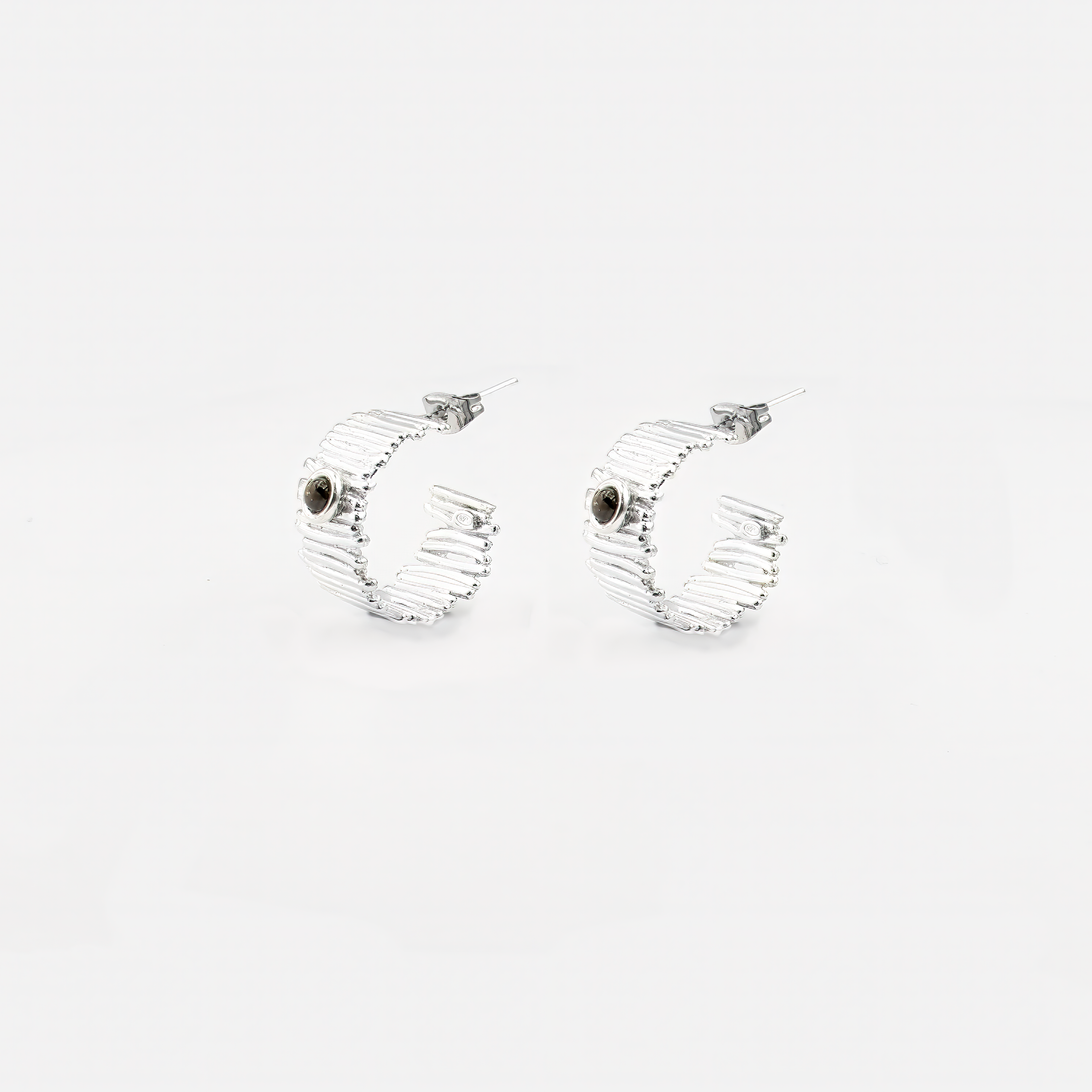 עגילי חישוק בעבודת יד מכסף 925, משובצים סמוקי טופז בגוון חום מעושן – תכשיט בעל אופי מיוחד, שמתאים לנשים שמחפשות סטייל עם עומק. האבן יוצרת מראה אלגנטי עם טוויסט מחוספס אך עדין, כזה שמשתלב נהדר עם כל צבע עור וביגוד ניטרלי או כהה. החישוק הקליל והמדויק מעניק תנועה נעימה ותחושת זרימה, בעוד האבן מוסיפה נוכחות שקטה. תכשיט מושלם כמתנה ייחודית ליום הולדת, לאירוע חשוב או לעצמך – כתזכורת לעוצמה פנימית ולחיבור אל הקרקע.

