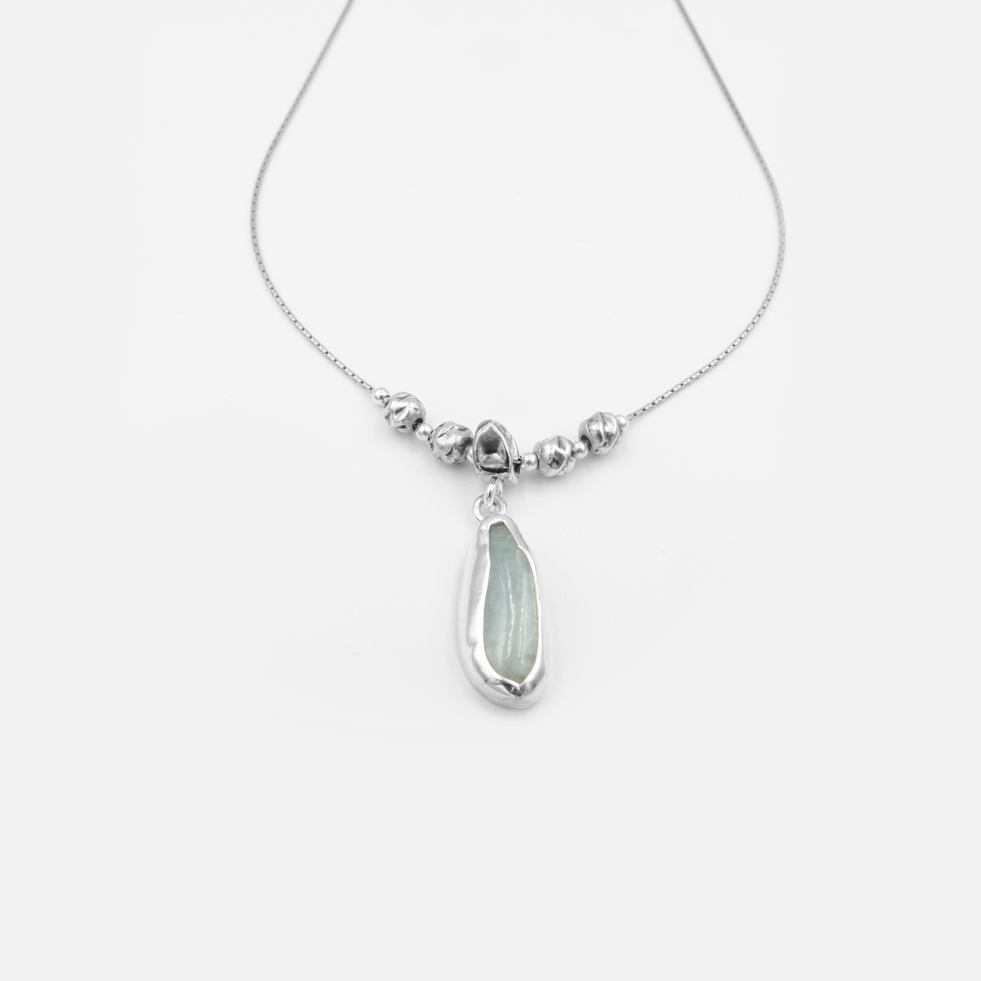 שרשרת כסף אלגנטית בעיצוב ייחודי, עם תליון בצורת טיפה לא סימטרית משובץ אבן טבעית בגוון תכלת רך. מרכז השרשרת מעוטר בחרוזי כסף בעבודת יד, אשר מעניקים לה מראה אורגני ואומנותי. שילוב של טבע ופשטות מודרנית, מושלם למראה יום-יומי עם טאץ' מתוחכם.