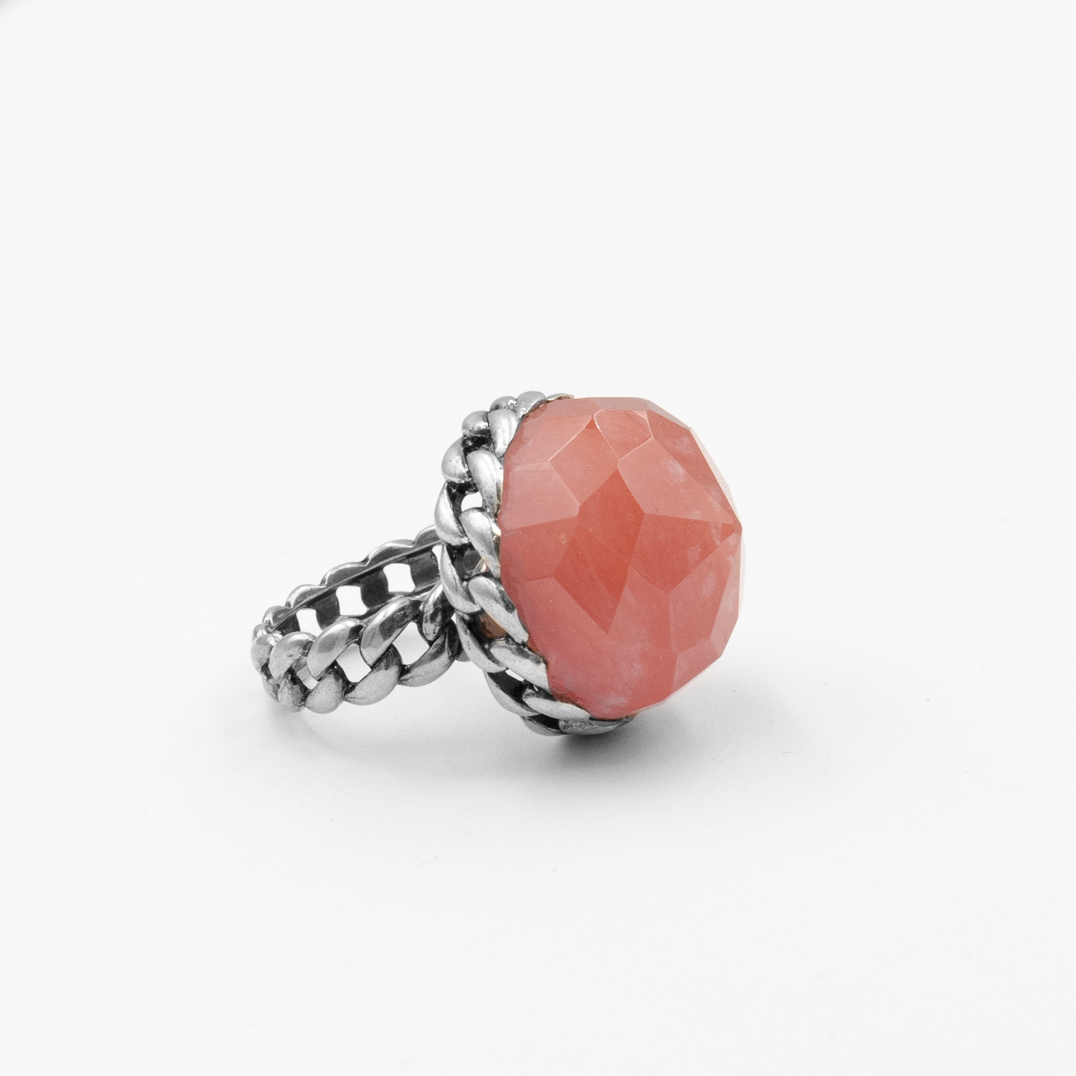 טבעת כסף עוצמתית מלאת תשומת לב, כוללת באבן גדולה בגוון ורוד־קורל עם חיתוך פאות (faceted) שמבליט את הזוהר את הברק והעומק של האבן. העיצוב משלב בסיס כסף בעבודת חריטה בסגנון שרשרת, המעניק לטבעת מראה חזק אך אלגנטי, שמזכיר טבעת שרשרת או סגנון בוהו וינטג' מתוחכם. האבן הגדולה הופכת את הטבעת לאקססורי בולט, כזה שלא עובר מתחת לרדאר, אך שומר על איזון אסתטי. גוון האבן מחמיא לעור, מתאים לקיץ ולחורף כאחד, ויוצר ניגוד יפהפה עם גוון המתכת. תכשיט מיוחד שמדגיש אישיות, טעם ייחודי ואמירה אישית לא שגרתית. מושלמת כטבעת מתנה, ליום