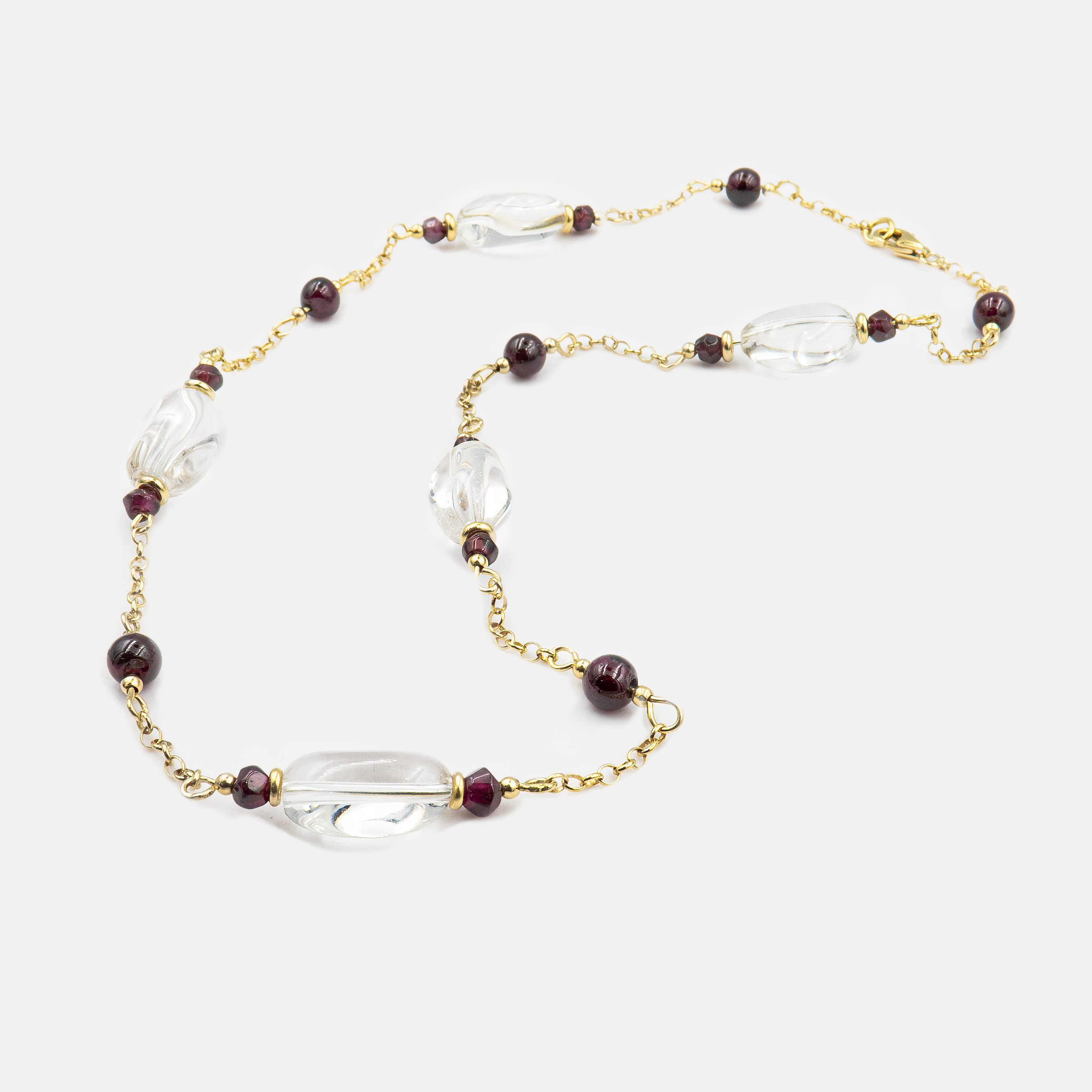 תקריב של תכשיט ייחודי – שרשרת זהב אמיתי 14 קראט עם שני תליונים קטנים: גארנט בוהק ורוק־קריסטל שקוף. השילוב בין הצבע האדום העמוק לבין הזוהר השקוף יוצר קונטרסט מרהיב אך עדין, שמסמל גם אנרגיה רגשית וגם בהירות רוחנית. עיצוב מינימליסטי ואלגנטי, עשוי בעבודת יד, ומתאים לכל מי שמחפשת תכשיט עם משמעות עמוקה, מראה קלאסי ונוכחות רכה עם קריצה אישית.