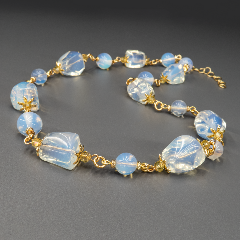 ענק עדין ובעל נוכחות – שילוב של מונסטון בגווני לבן־כחלחל עם אבני אופליט בגימור חלבי וזוהר פנימי. התוצאה היא תכשיט מלא אור, תחכום וקסם טבעי. כל אבן מקרינה עדינות שקטה, ומתאימה לנשים שמבקשות לשלב בין אלגנטיות ורוחניות בלבושן היומיומי או לאירוע מיוחד.

