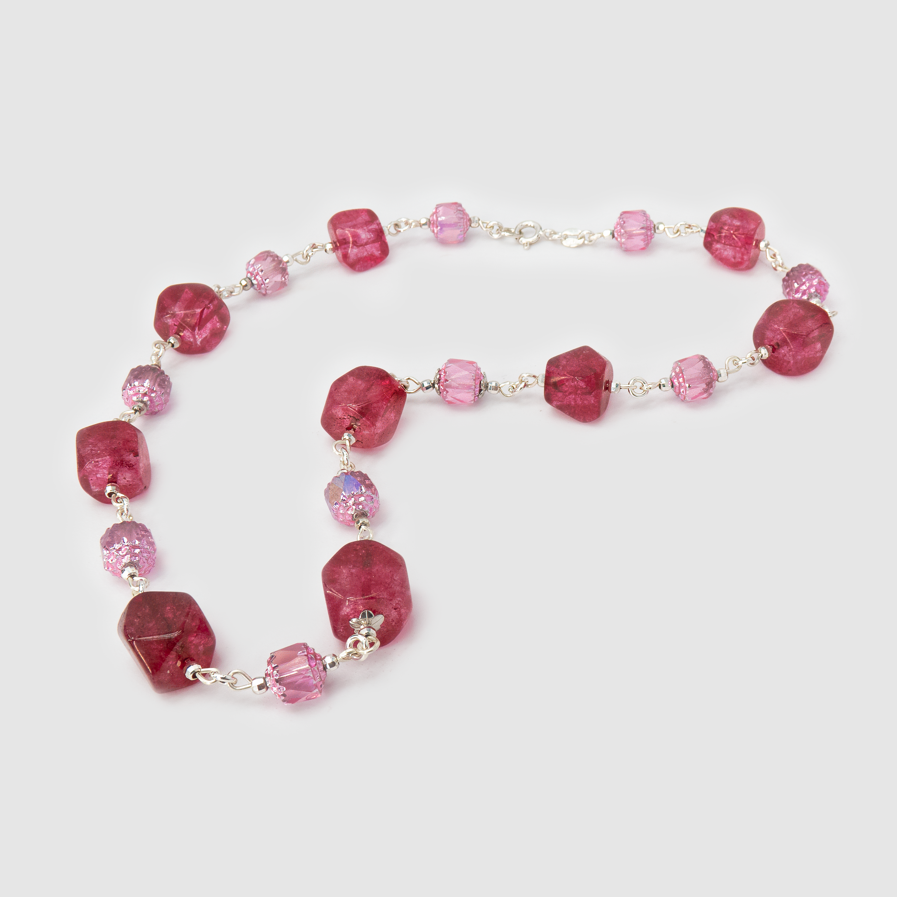 שרשרת בעבודת יד בשילוב אבנים בגווני ורוד עדין ובורדו עמוק – שילוב בין רוך לנוכחות. האבנים מסודרות בהרמוניה צבעונית שמזכירה פרחי שושן ויין אדום. תכשיט אלגנטי ועשיר בגוונים חמים, מתאים ליום ולערב, ומוסיף עומק מתוחכם לכל הופעה.