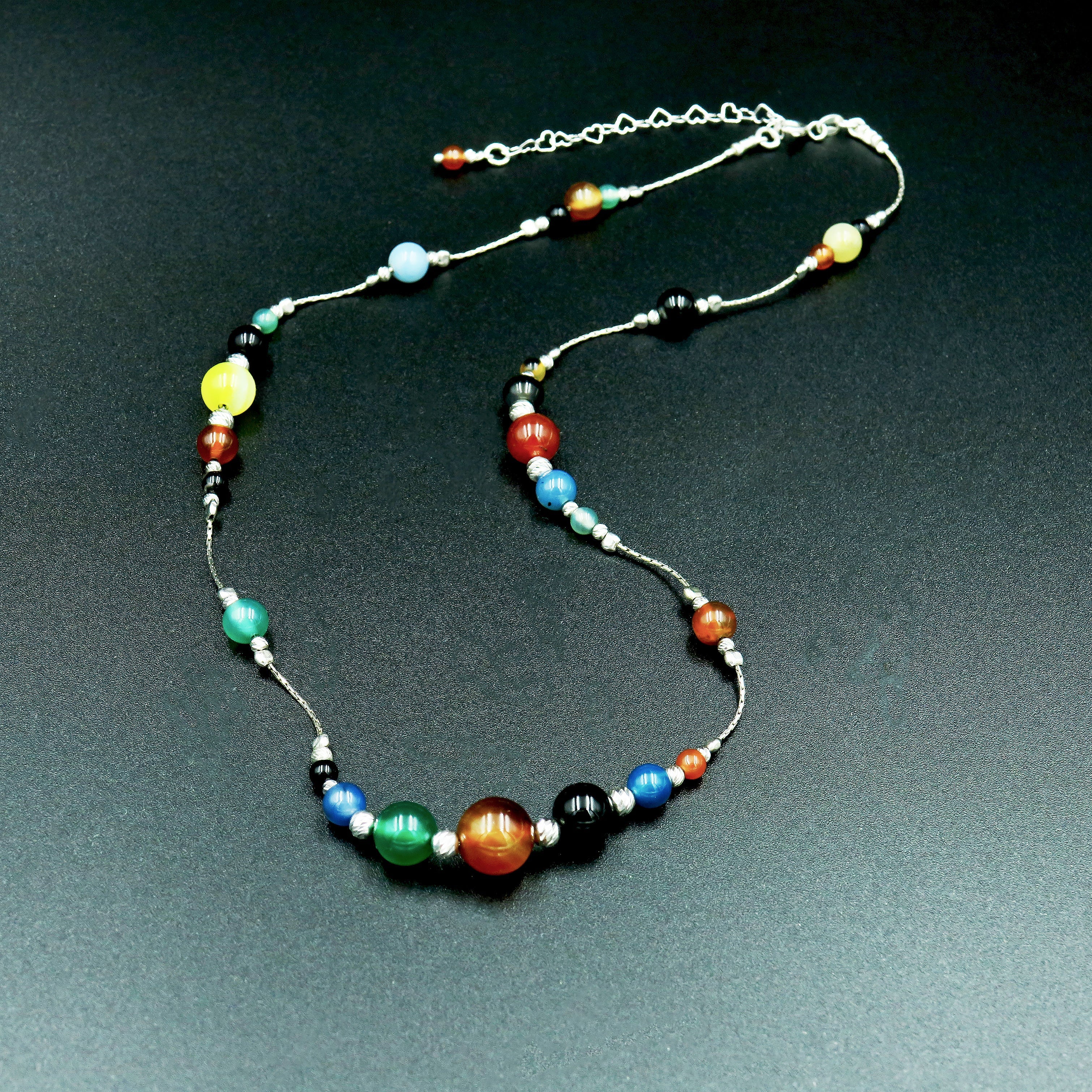 תכשיט אקספרסיבי שמביא איתו עולם שלם של צבע ואור – שרשרת משובצת אבני אגת בשלל גוונים משתנים, בעבודת יד מדויקת, עם חיבורי כסף 925 למראה מהודק ואיכותי. תוספת מושלמת למי שאוהבת לבטא את האישיות שלה דרך תכשיטים, ולשלב טבע ואלגנטיות יחד.

