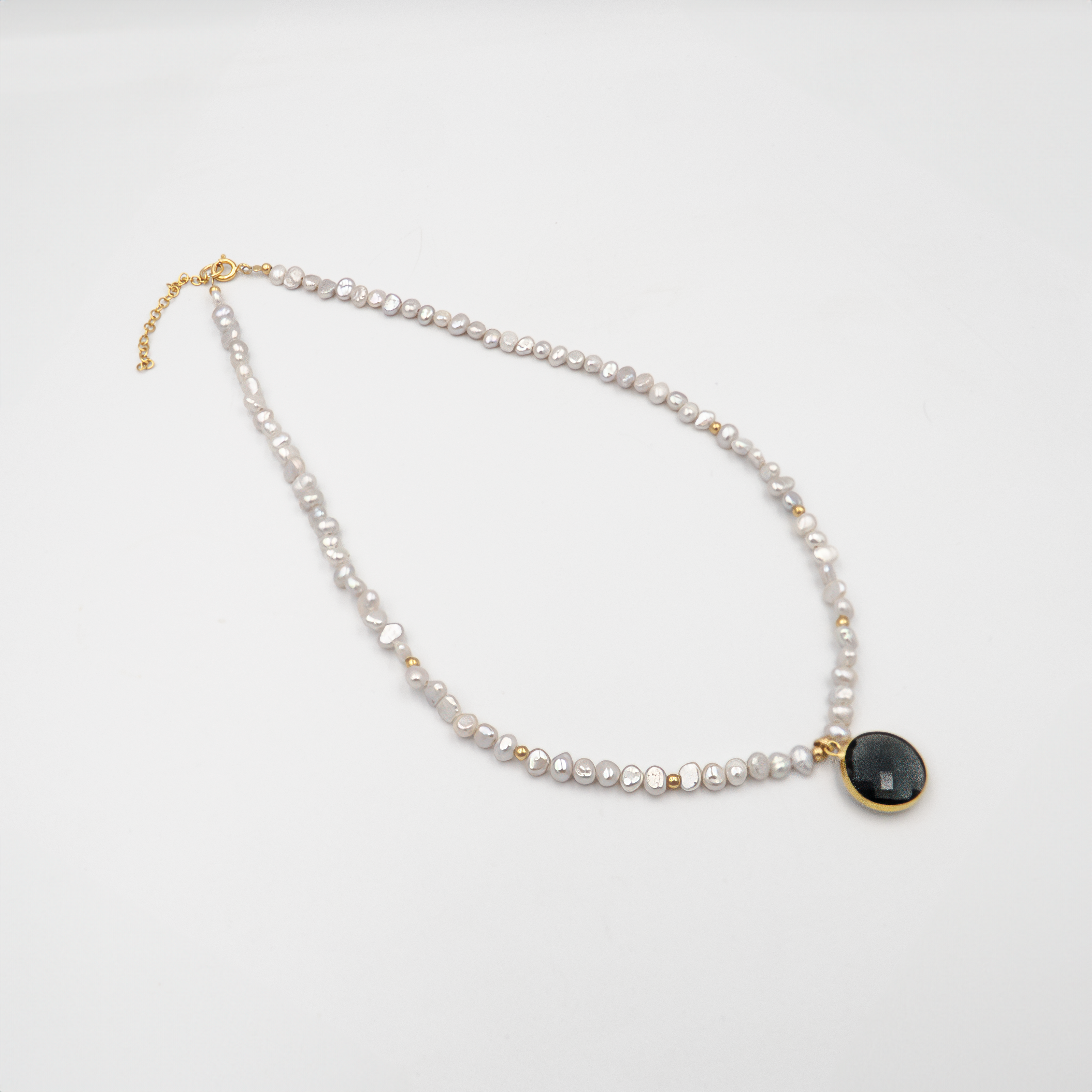 שרשרת אלגנטית עם פניני לבנדר עם תליון מרכזי – תכשיט בעלת מראה רך ויוקרתי. הפנינים סגלגלות ובעלות ברק פנינתי טבעי, מעניקות לשרשרת אווירה חלומית ונשית. התליון משתלב בצורה הרמונית עם רצף הפנינים, מוסיף נקודת מוקד עיצובית ומאזן בין פשטות לרושם. מתאימה לענידה ביום יום וגם לאירועים מיוחדים – מושלם למי שמחפשת צבע לא שגרתי באלגנטיות.