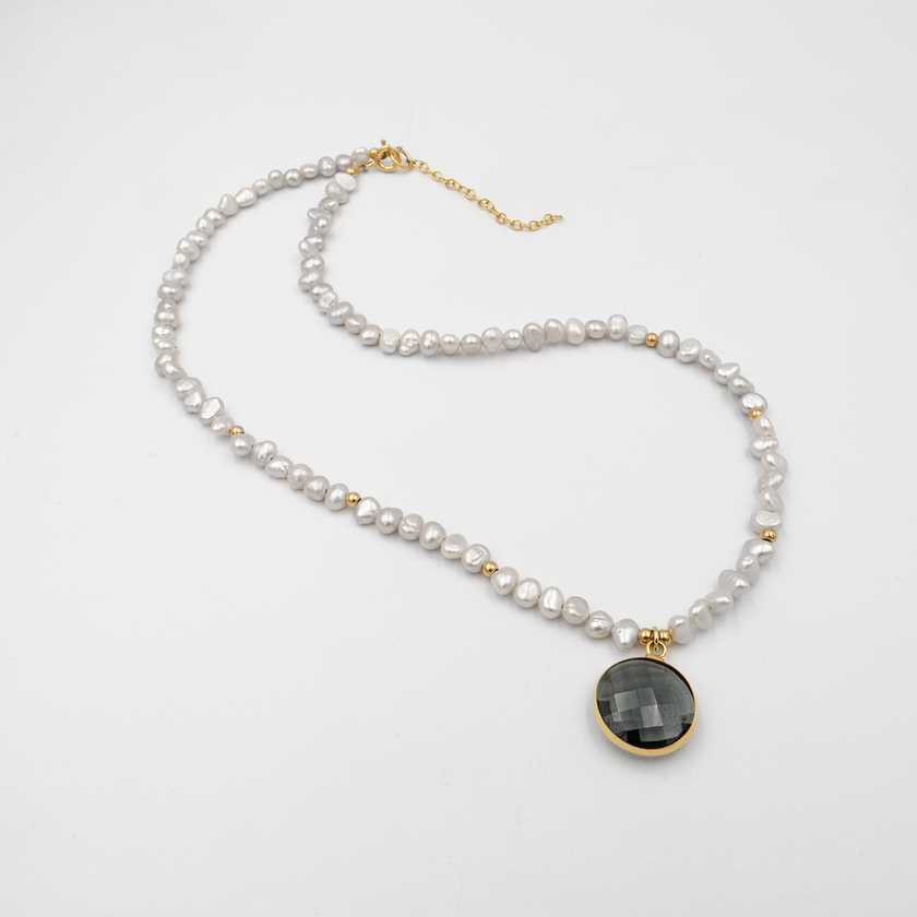 שרשרת פנינים בצבע לבנדר עדין עם תליון מרכזי – תכשיט בעלת מראה רך ויוקרתי. הפנינים סגלגלות ובעלות ברק פנינתי טבעי, מעניקות לשרשרת אווירה חלומית ונשית. התליון משתלב בצורה הרמונית עם רצף הפנינים, מוסיף נקודת מוקד עיצובית ומאזן בין פשטות לרושם. מתאימה לענידה ביום יום וגם לאירועים מיוחדים – תכשיט יוצא דופן שמחמיא לעור.