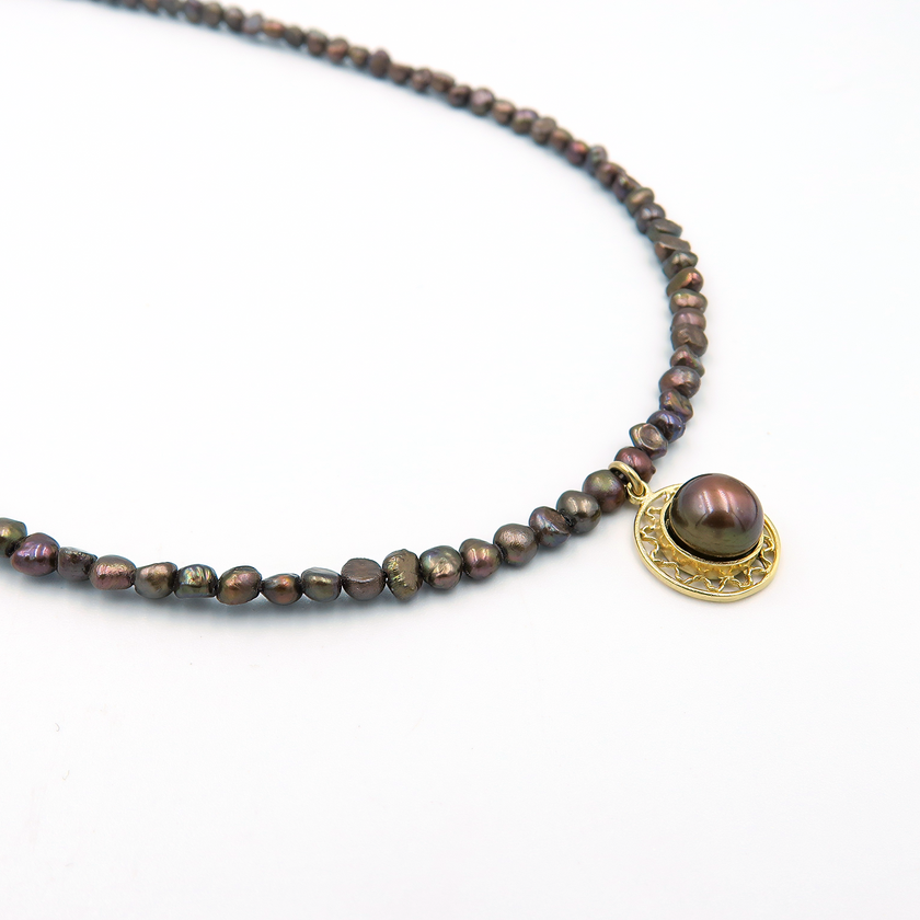 שרשרת פנינים בגווני שוקולד עשירים עם תליון מרכזי – פריט ייחודי עם ניחוח של יוקרה שקטה. הפנינים בצבעי חום, ברונזה וקוניאק יוצרים מראה עשיר בגוונים טבעיים שמתאים לכל עונה. התליון מוסיף נגיעה עיצובית מרכזית שמושכת תשומת לב, שמושך את העין ומשלים את המראה הכללי. השילוב בין גווני האדמה לבין הברק הפנינתי מעניק לשרשרת תחושת עושר שקט וסטייל מודרני, שמתאימים גם ליום וגם לערב. שרשרת שמתחברת לנשיות חזקה, לאהבה לפרטים ולאיזון בין עוצמה לרוך – בדיוק במידה הנכונה.