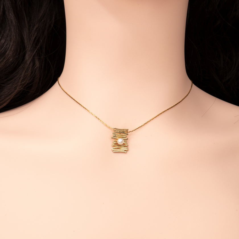 תליון זהב מעוצב בעבודת יד בצורת פסים גולמיים ובמרכזו פנינה טבעית קטנה. השרשרת הדקה משלימה את המראה הנקי והעכשווי, שמעניק תחושת יוקרה רכה. פריט מושלם לאירועים, אך גם ללבישה יום-יומית עם סטייל.