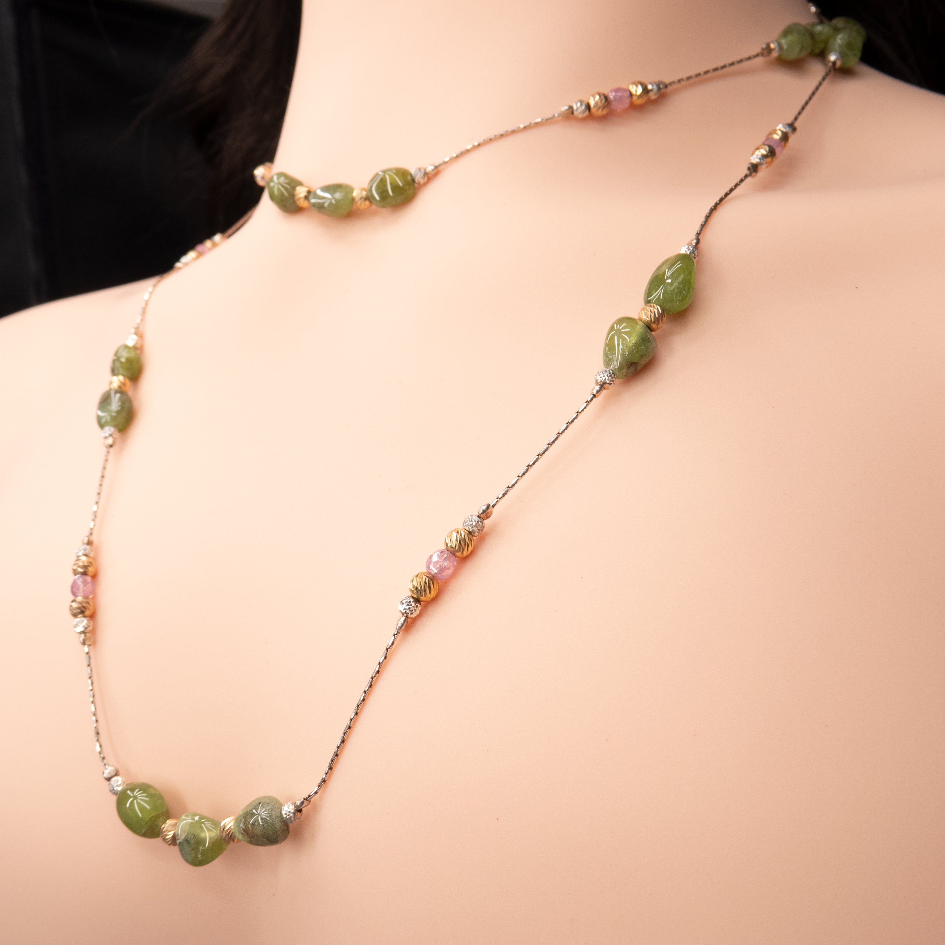 שרשרת ארוכה בעיצוב בוהו-שיק, עם אבנים ירוקות טבעיות בעלות צורה אורגנית, בשילוב חרוזים כסופים, מוזהבים ואמייל בגוון ורוד. השרשרת מורכבת על חוט כסף דק בגוון מבריק, ומונחת ברכות על רקע ורוד בהיר. השילוב בין מרקמים וצבעים יוצר תחושת יוקרה עדינה עם נגיעה אומנותית.
המחיר מתייחס לשרשרת אחד בבד