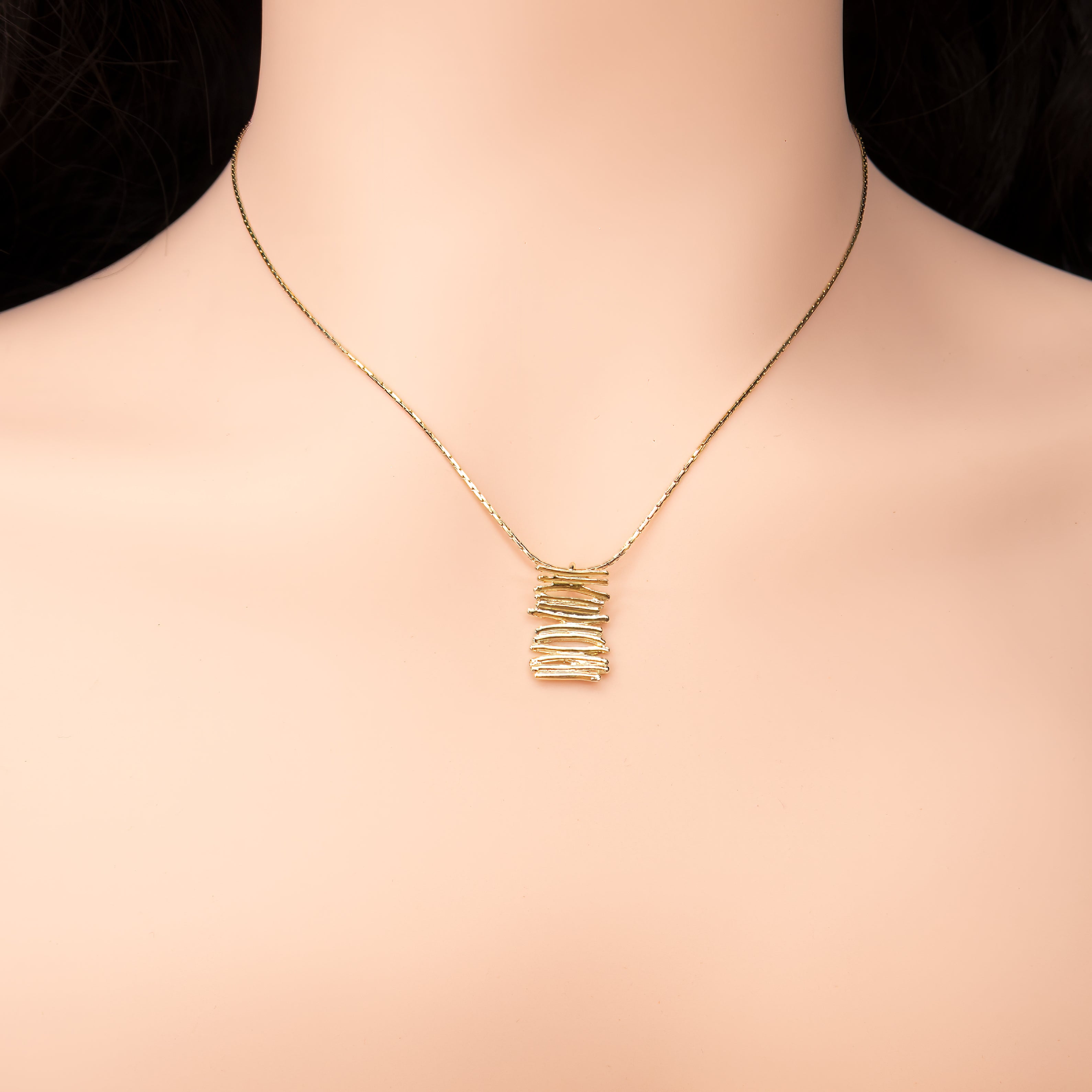 שרשרת זהב עדינה עם תליון גאומטרי מודרני בצורת מקלות או פסים מוערמים, היוצרים מבנה תלת-ממדי מרתק. העיצוב משדר אלגנטיות מינימליסטית עם קריצה לעולם הטבע והטקסטורות האורגניות. תכשיט מושלם ללבישה יומיומית עם טוויסט עיצובי.