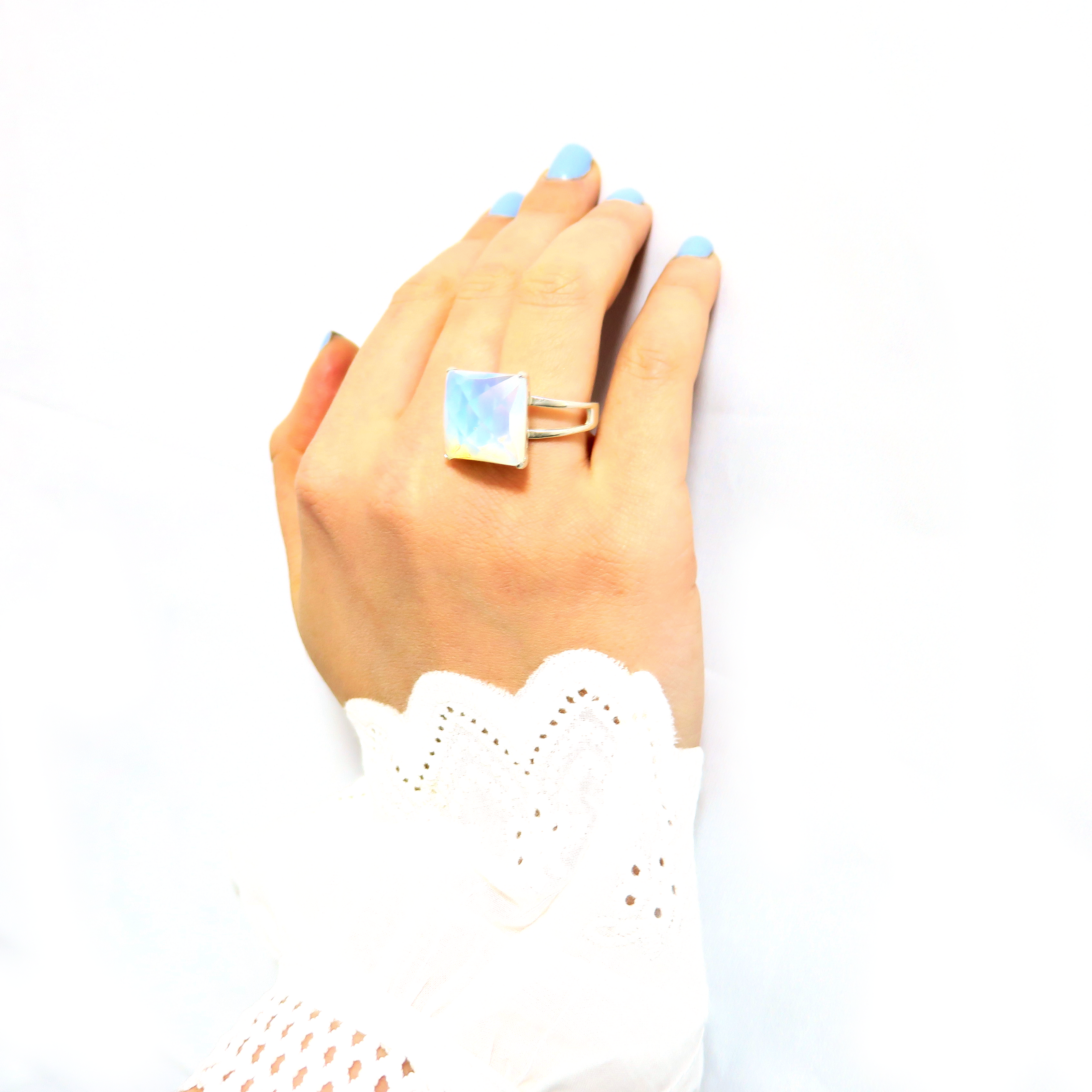 טבעת כסף בעבודת יד, כוללת באבן אופליט לבנה אובלית בעלת מראה חלק ועדין. האבן הלבנה משדרת אור שקט, עם גוון שמזכיר ערפל בוהק שמשתנה בהתאם לזווית התאורה – לעיתים כמעט שקוף, לעיתים בוהק כקרן ירח. הטבעת משלבת עיצוב מינימליסטי עם אופי עדין ובולט. השיבוץ הנקי והחלק מדגיש את יופייה הטבעי של האבן, ויוצר תכשיט שמביא איתו שקט פנימי וזרימה רכה. המתכת הכסופה והברק הפנימי של האופליט משתלבים למראה שמשדר איזון בין אלגנטיות קלאסית לרוח מודרנית רגישה. טבעת שמתאימה לאירועים חגיגיים או ליום־יום עם נגיעה אישית ומיוחדת. תכשיט שמת