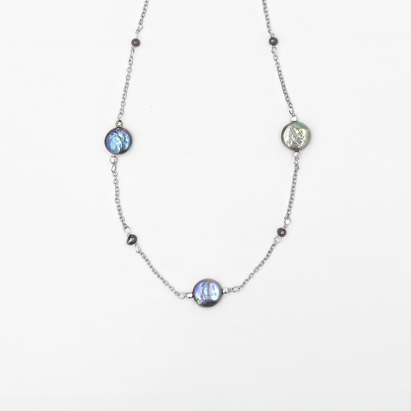 שרשרת מינימליסטית עם פנינים כהות בעבודת יד – תכשיט אלגנטי ונקי, שמשלב מראה מודרני עם עומק צבע טבעי. הפנינים העגולות בגוון אפור־כחלחל כהה משתלבות על גבי שרשרת כסף עדינה ומוסיפות לה אור עמוק עם אפקט מסתורי. העיצוב מדויק, מסוגנן ונשי – מתאים לנשים שמעדיפות תכשיטים מתוחכמים שאינם צועקים אך אי אפשר להתעלם מהם. השרשרת מושלמת ללבישה יומיומית אלגנטית או כשרשרת שמשלימה הופעה עם טעם טוב ועדינות.