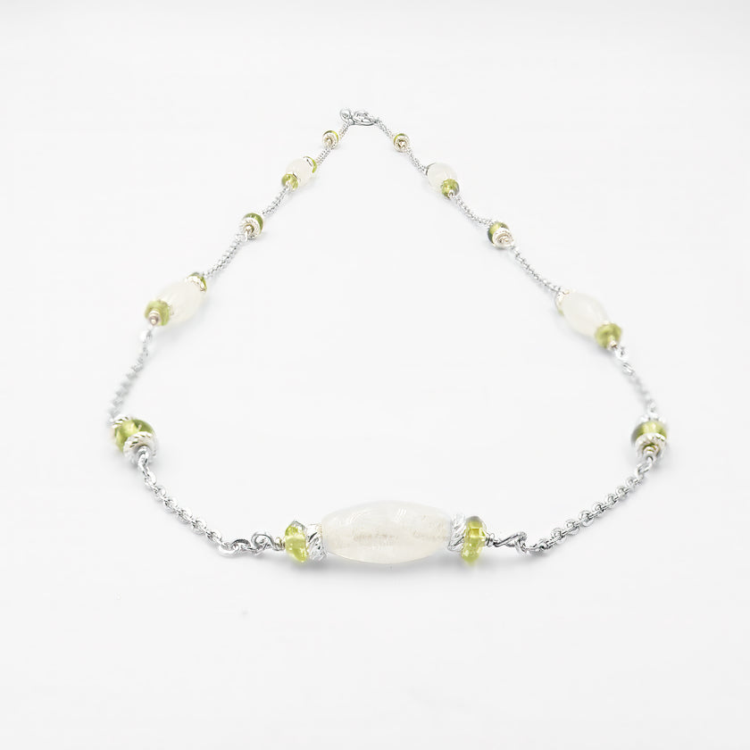 שרשרת מעודנת מזהב 14 קראט עם שילוב אלגנטי של מונסטון לבן חלבי ואוליבין ירוק רך, בעבודת יד מוקפדת. תכשיט נשי עם גוונים טבעיים, המשלב אור רך ורעננות חיה. המונסטון מביא עמו אנרגיה של אינטואיציה ועדינות, בעוד האוליבין תורם לתחושת קלילות והתחדשות. עיצוב אלגנטי ונקי שמתאים לכל סגנון לבוש – קז'ואל, בוהו או קלאסי. תכשיט מושלם כמתנה סמלית עם משמעות רגשית, רוחנית ואסתטית, בעיצוב שמשדר פשטות יוקרתית ונוכחות רגישה.