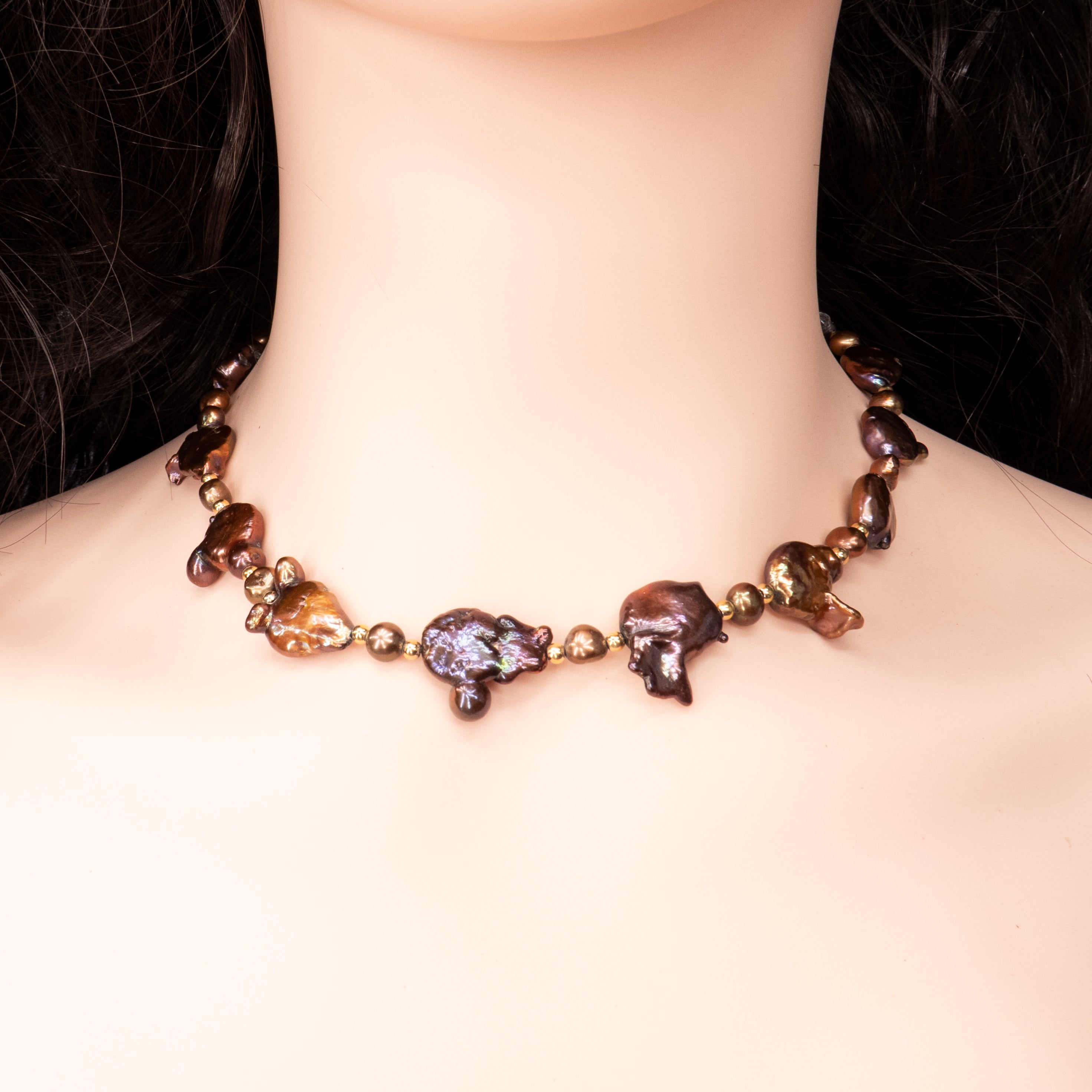 פריט בעיצוב לא שגרתי, מלא נוכחות המורכבת מפניני בארוק טבעיות בגוון שוקולד עמוק, עם אביזרים בציפוי זהב שמדגישים את צורתן הבלתי אחידה והמרקם החי של כל פנינה. הברק המטאלי החם של הפנינים משתלב באופן הרמוני עם הנגיעות המוזהבות, ויוצר ניחוח של טבע פראי ואלגנטי יחד. שילוב בין חוזק טבעי ליוקרה נינוחה – אידיאלי לאירוע ערב, להופעה עם אמירה או כמתנה מרשימה לאישה מיוחדת. פניני הבארוק, כל אחת עם אישיות משלה, הופכות את השרשרת הזו לשרשרת שלא דומה לשום דבר אחר – טבעית, אותנטית ומרשימה.