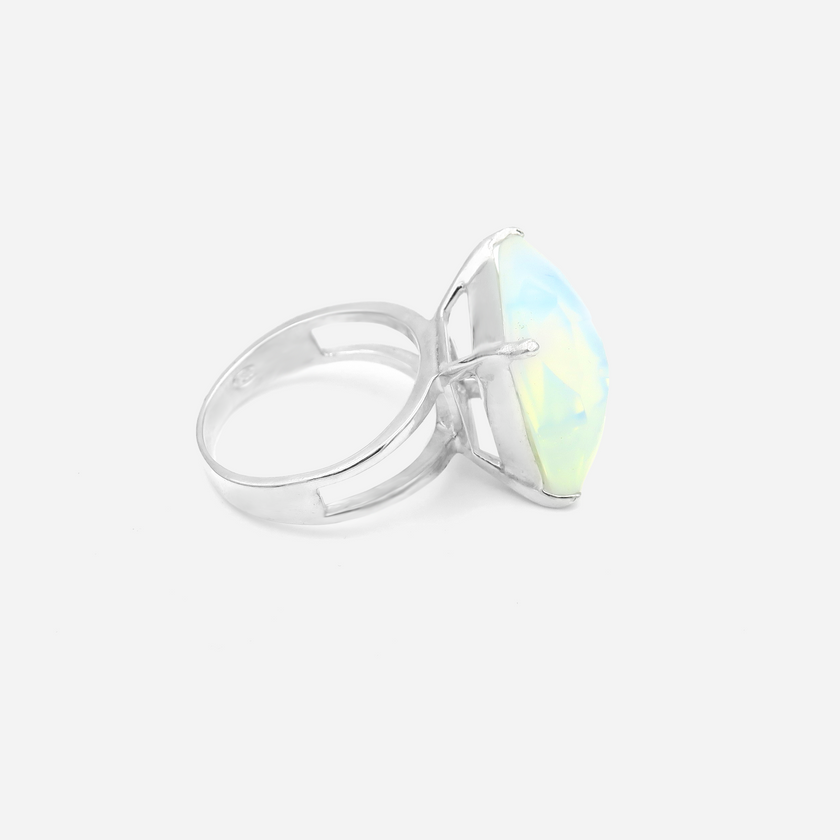 טבעת כסף בעבודת יד, משולבת באבן אופליט לבנה אובלית בעלת מראה חלק ועדין. האבן הלבנה משדרת ברק עדין, עם צבע לבן־ענן שמשתנה בהתאם לזווית התאורה – לעיתים כמעט שקוף, לעיתים בוהק כקרן ירח. הטבעת משלבת עיצוב מינימליסטי עם אופי עדין ובולט. השיבוץ הנקי והחלק מדגיש את יופייה הטבעי של האבן, ויוצר תכשיט שמביא איתו איזון, בהירות ועדינות. המתכת הכסופה והברק הפנימי של האופליט משתלבים למראה שמשדר איזון בין אלגנטיות קלאסית לרוח מודרנית רגישה. טבעת שמתאימה לאירועים חגיגיים או ליום־יום עם נגיעה אישית ומיוחדת. תכשיט שמתחבר לתח