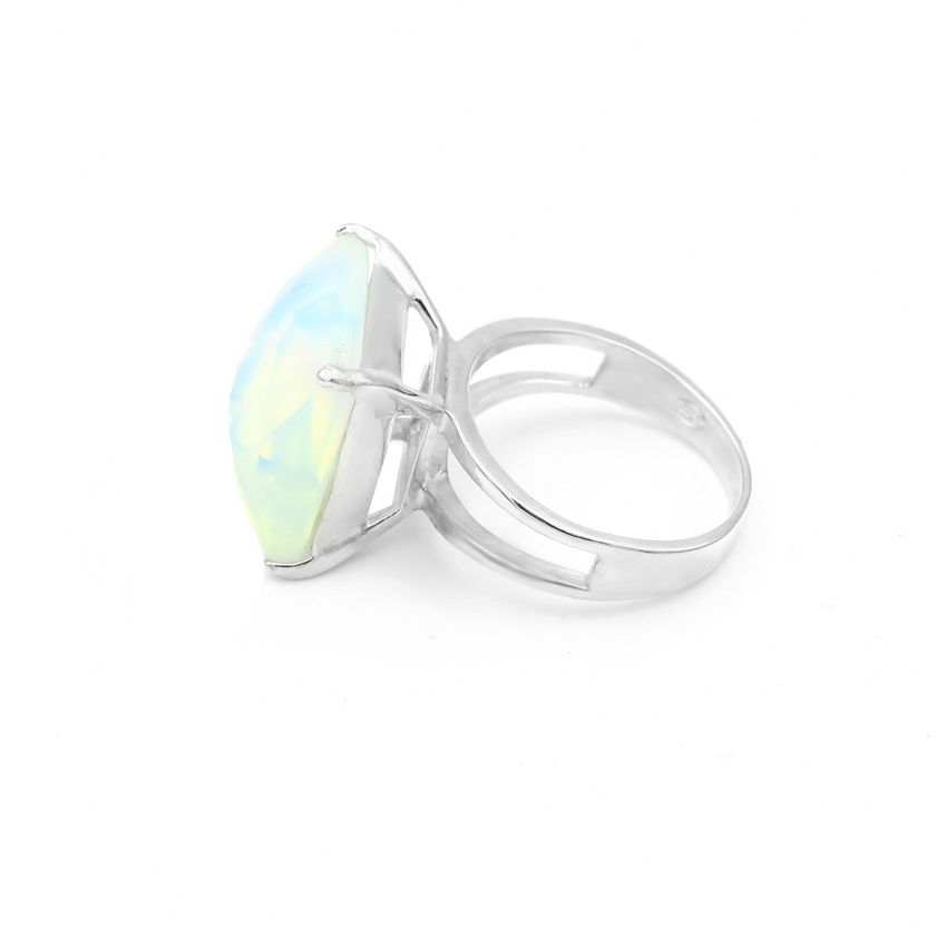 טבעת כסף בעבודת יד, מעוטרת באבן אופליט לבנה אובלית בעלת מראה חלק ועדין. האבן הלבנה משדרת אור שקט, עם שקיפות פנינתית שמשתנה בהתאם לזווית התאורה – לעיתים כמעט שקוף, לעיתים בוהק כקרן ירח. הטבעת משלבת עיצוב מינימליסטי עם רוך מלכותי. השיבוץ הנקי והחלק מדגיש את יופייה הטבעי של האבן, ויוצר תכשיט שמביא איתו רוגע, ניקיון פנימי וחמלה. המתכת הכסופה והברק הפנימי של האופליט משתלבים למראה שמשדר איזון בין אלגנטיות קלאסית לרוח מודרנית רגישה. טבעת שמתאימה לאירועים חגיגיים או ליום־יום עם נגיעה אישית ומיוחדת. תכשיט שמתחבר לתח