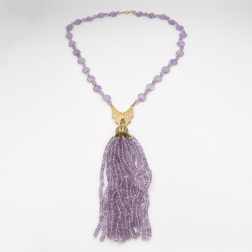 שרשרת ארוכה בעבודת יד, עשויה מחרוזי אמטיסט שקופים בגוון סגול בהיר, בגוון סגול שקוף־ענברי עדין, עם תליון כסוף מנצנץ בקצה. החרוזים יוצרים נוכחות עדינה אך בולטת, עם זרימה רכה וזוהר מתמשך. השרשרת מתאימה למראה ערב רומנטי, לאירוע חגיגי או אפילו ללבוש יומיומי שזקוק לנגיעה של קסם. האמטיסט נחשב לאבן של רוגע ואינטואיציה, והעיצוב כולו משדר שילוב של אלגנטיות רגישה. תכשיט עם אווירה נשית, מעודנת ומלאת הבעה – כזה שלא צריך מילים כדי לומר שהוא מיוחד.