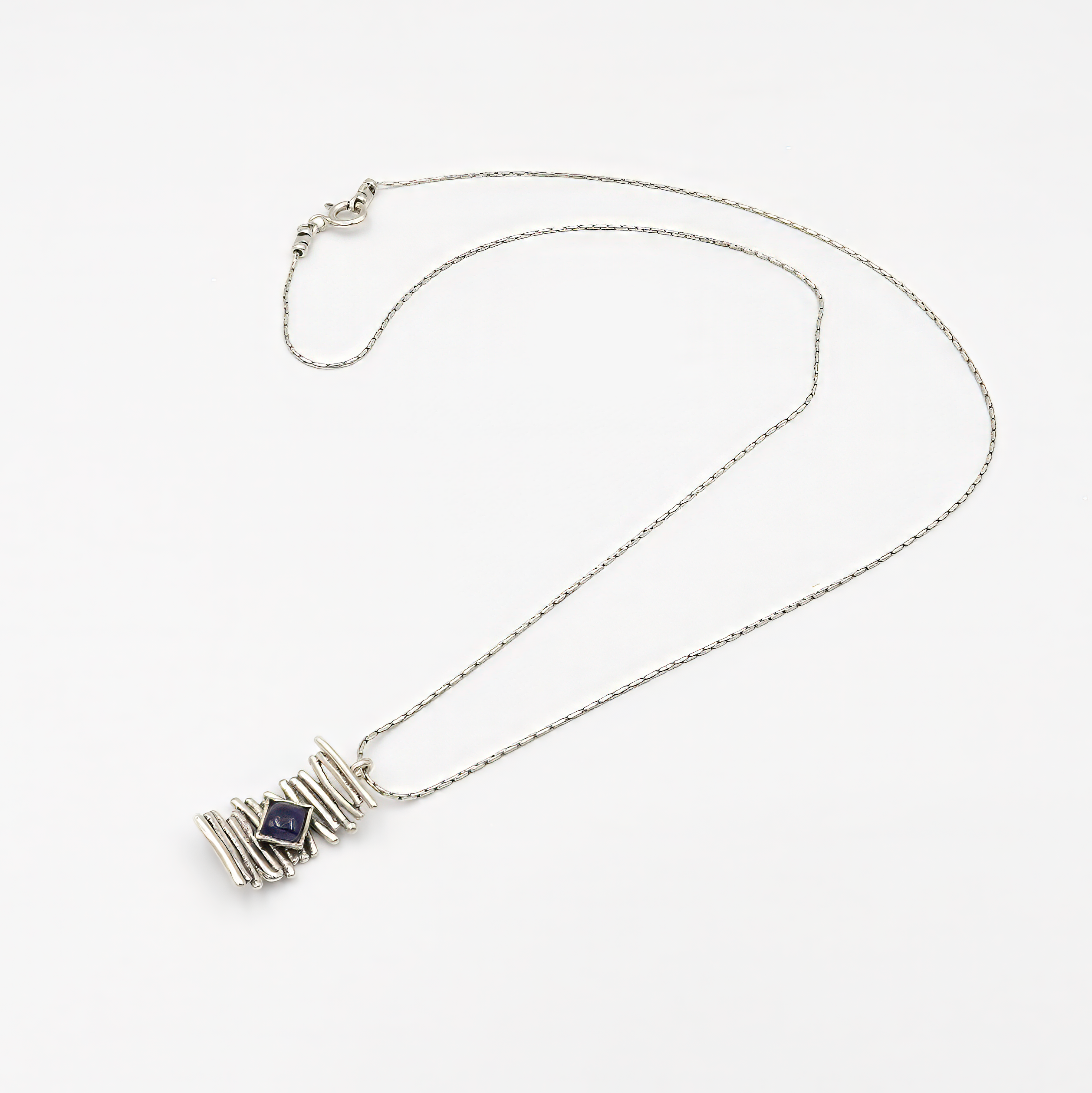 צילום תכשיט כסף קלאסי עם נוכחות שקטה: שרשרת דקה ועדינה עם חמישה חרוזים עגולים במרכזה, ומתחתיהם תליון עגול משובץ באבן איולייט כחולה-סגלגלה. האבן, בעלת ליטוש שטוח ושקיפות עדינה, משנה גוונים בהתאם לאור – מסגול כהה לכחול מעושן. התכשיט מושלם לנשים שאוהבות פריטים אלגנטיים עם טאץ' של קסם טבעי.

