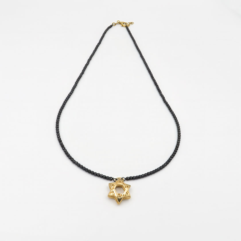 שרשרת כסף מעוצבת לגבר, בגוון מתכתי כהה למראה מודרני ועוצמתי. השרשרת מגיעה ללא אבנים, בקווים נקיים, עם תליון מגן דוד בעיצוב גאומטרי בגימור זהוב מבריק. הניגוד בין המתכת הכהה לתליון הזהוב יוצר אסתטיקה חזקה ונקייה, עם נוכחות חזקה וסגנון ייחודי. מגן הדוד בתכשיט מסמל זהות, עוגן תרבותי עם נגיעה עכשווית, ויושב בצורה מדויקת על הצוואר, מושך מבטים ומשדר אמירה ברורה. מתאים לגבר שמעריך עיצוב משמעותי, קווים ברורים ושילוב של מסורת וחדשנות. שרשרת שיכולה להשתלב בלבוש יומיומי וגם להוות פריט אמירה לאירועים מיוחדים – פריט שמשל
