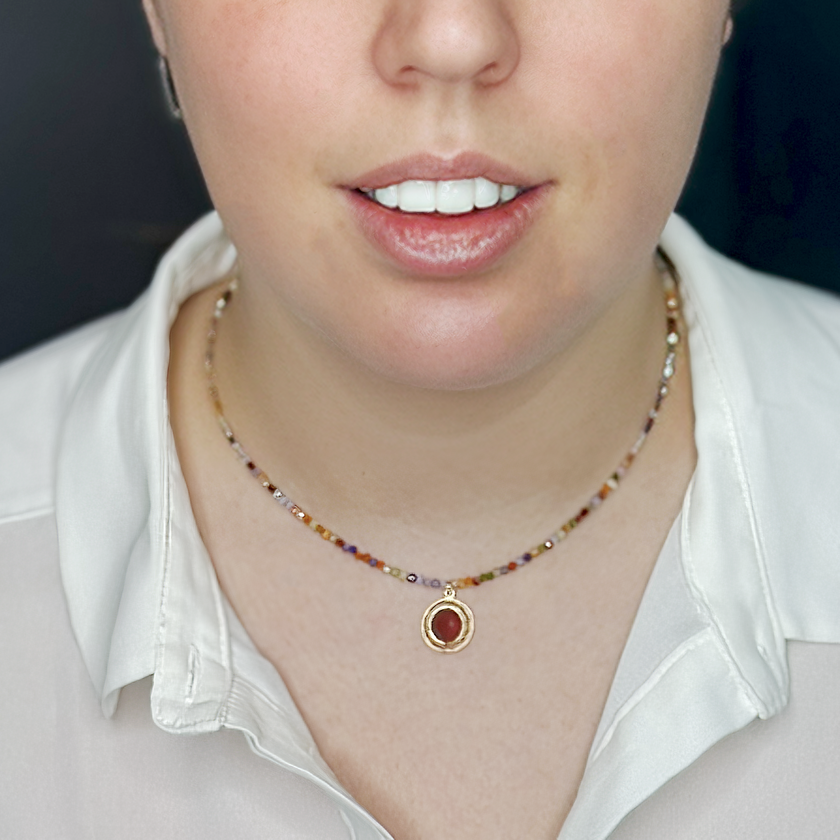 שרשרת אבני חן צבעוניות בגווני קשת עדינים עם תליון קורנליאן עגול במרכז – נגיעה צבעונית עם עוצמה רגשית. החרוזים הקטנים בגווני כחול, כתום, סגול וירוק יוצרים רקע עשיר שמבליט את הנוכחות של האבן, שהוא לב התכשיט. הקורנליאן, אבן הידועה באיכויותיה המחזקות והממריצות, משתלבת כאן בעיצוב שמחבר בין הרמוניה חזותית לאופי אישי. אביזר מלא חיים למי שאוהבת צבע וחום – כזה שמכניס צבע, תחושת חיוניות וחיבור לטבע אל תוך ההופעה שלך.