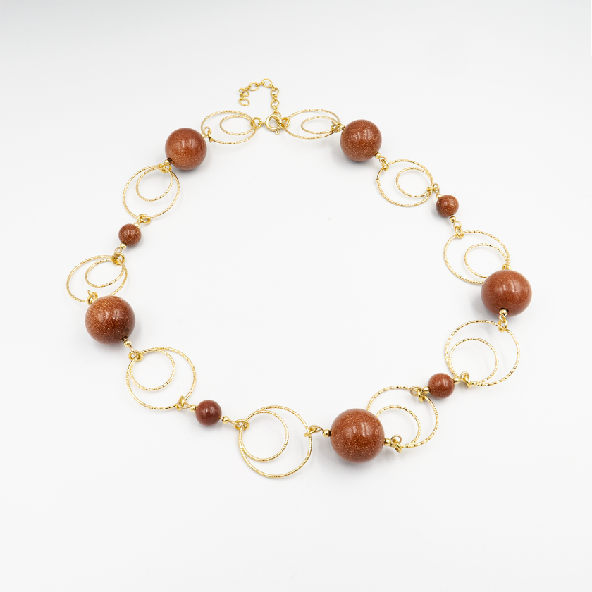 שרשרת אוונטיורין חום בעבודת יד, עם חרוזים בגודל בינוני־גדול בגווני חום־קינמון וחום־אדמה. האבנים בגימור חצי־מבריק מעניקות תחושת רכות ועומק בו־זמנית. תכשיט שמתאים גם למראה יום וגם לערב באווירה חמה ורגועה. נוגע בנשיות רגישה, מחוברת וטבעית – ובעל מראה נצחי שלא תלוי בטרנדים.