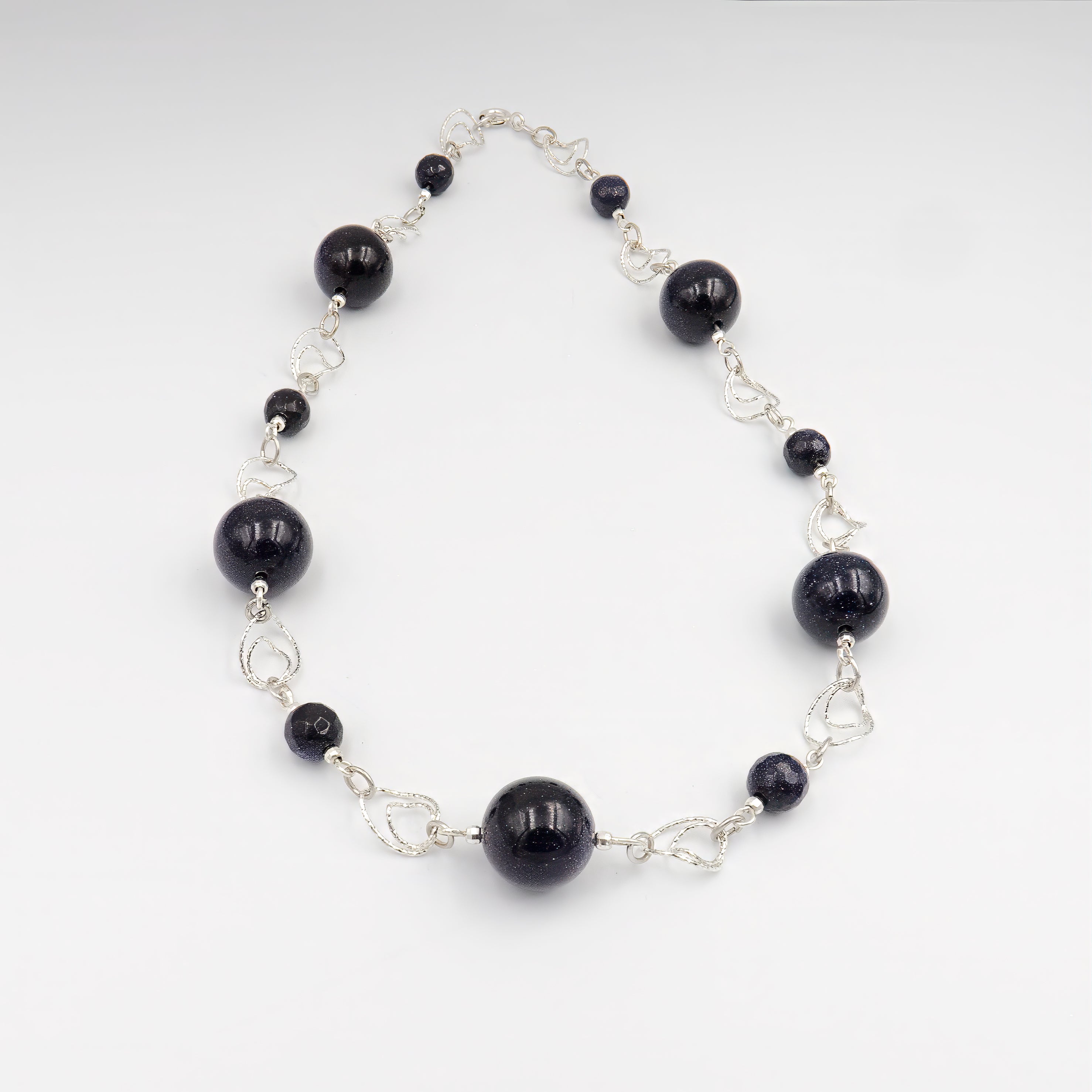 שרשרת אוונטיורין כחול בעבודת יד, עם אבנים בגווני כחול עמוק, כחול לילה וניואנסים של כחול־אפור רך. האבנים בוהקות באור פנימי כמו שמיים נקיים בשעת בין ערביים. הגימור החלק־מבריק של החרוזים מעניק לתכשיט נוכחות שקטה אך מהפנטת. עיצוב שמשדר רוגע, ביטחון ושקט פנימי. מתאים לנשים שמבקשות להוסיף עומק, איזון ותחכום להופעה יומיומית או למראה ערב מעודן ומעודכן.

