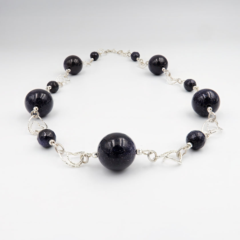 שרשרת בעבודת יד עם אבני אוונטיורין בגווני כחול עמוק עד כחול־שחור, בגימור מט משולב ברק פנימי קליל. האבנים משדרות אנרגיה של ריכוז, בהירות וניקיון רגשי. עיצוב קלאסי עם טוויסט מודרני, שמתאים לכל עונה ולמגוון סגנונות לבוש. תכשיט מושלם לאישה שמחפשת שילוב בין רוחניות ואסתטיקה, בין טבע ליוקרה רגועה.

