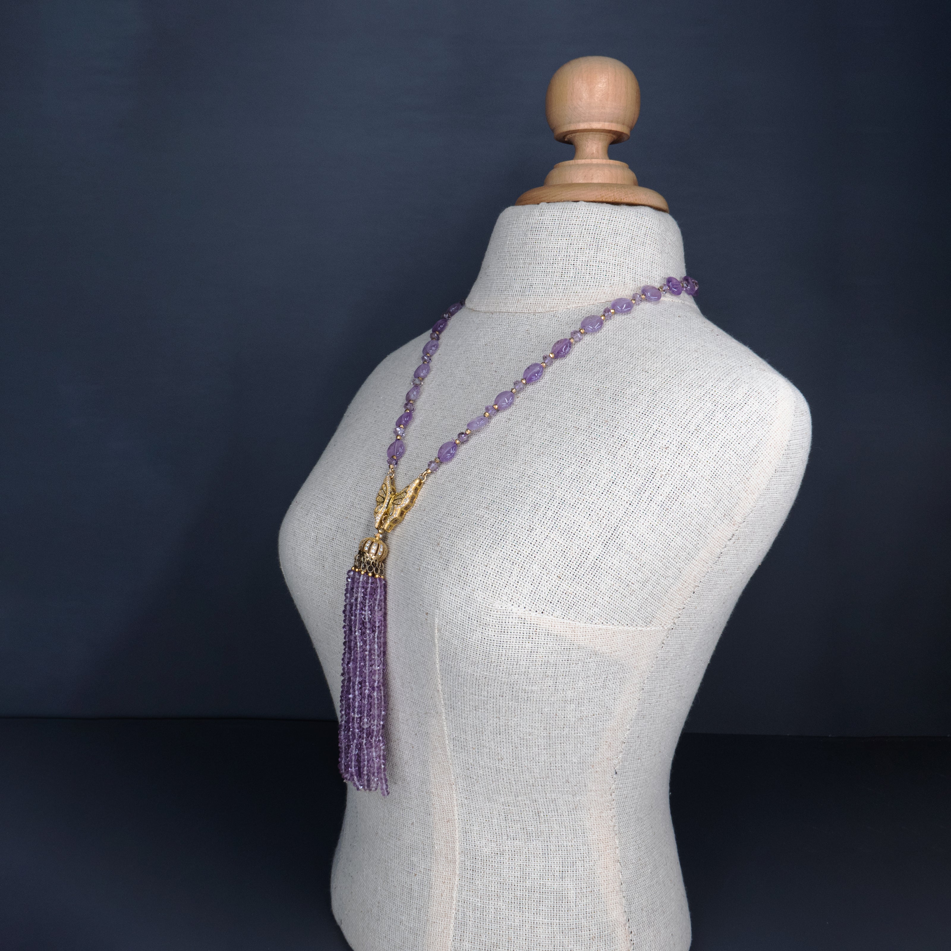 שרשרת ארוכה בעבודת יד, עשויה מחרוזי אמטיסט שקופים בגוון סגול בהיר, בגוון סגול שקוף־ענברי עדין, עם גדיל קריסטלים בוהק בקצה. החרוזים יוצרים נוכחות עדינה אך בולטת, עם תחושת קלילות ואלגנטיות בתנועה. השרשרת מתאימה למראה ערב רומנטי, לאירוע חגיגי או אפילו ללבוש יומיומי שזקוק לנגיעה של קסם. האמטיסט נחשב לאבן של רוגע ואינטואיציה, והעיצוב כולו משדר עיצוב נשי עם נגיעה מודרנית. תכשיט עם אווירה נשית, מעודנת ומלאת הבעה – כזה שלא צריך מילים כדי לומר שהוא מיוחד.