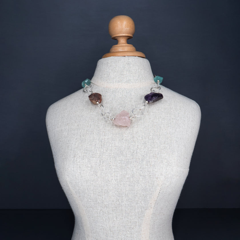 שרשרת כסף בעבודת יד שמשלבת מגוון עשיר של קריסטלים טבעיים – אמטיסט בגוון סגול עמוק, רוז קוורץ ורדרד ורך, פלואוריט בגוני ירוק וסגול שקופים, וקרנליאן חם בצבע כתום־אדמדם. ההשילוב הטבעי מקרין חום ונשיות עם עומק רגשי ואנרגטי, וכל אבן מוסיפה שכבה משלה של משמעות ונוכחות. השרשרת עוצבה כך שכל אבן תוכל לנשום, ומשלב ביניהן תוך כדי משחק של צבעים, טקסטורות ושקיפויות. השרשרת לנשים שמחפשות עומק ומשמעות באביזרים שלהן, כאלה שמתחברות לעוצמה שקטה ולסטייל ייחודי – וגם לאלו שמחפשות איזון, השראה ורוך. תכשיט שהוא גם יופי וגם חוויה