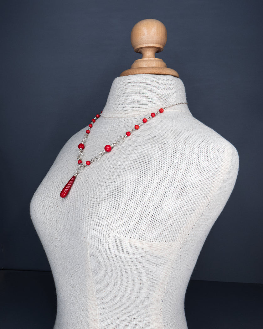 תמונה של תכשיט צבעוני ונועז – שרשרת כסף עם חרוזים בגוונים אדומים חזקים מאלמוג סינתטי, בשילוב טבעות טקסטורליות עדינות. תליון טיפה מרכזי מעניק נקודת מוקד ברורה, והעיצוב מתאים לקיץ, אירועים או יום־יום עם סטייל.