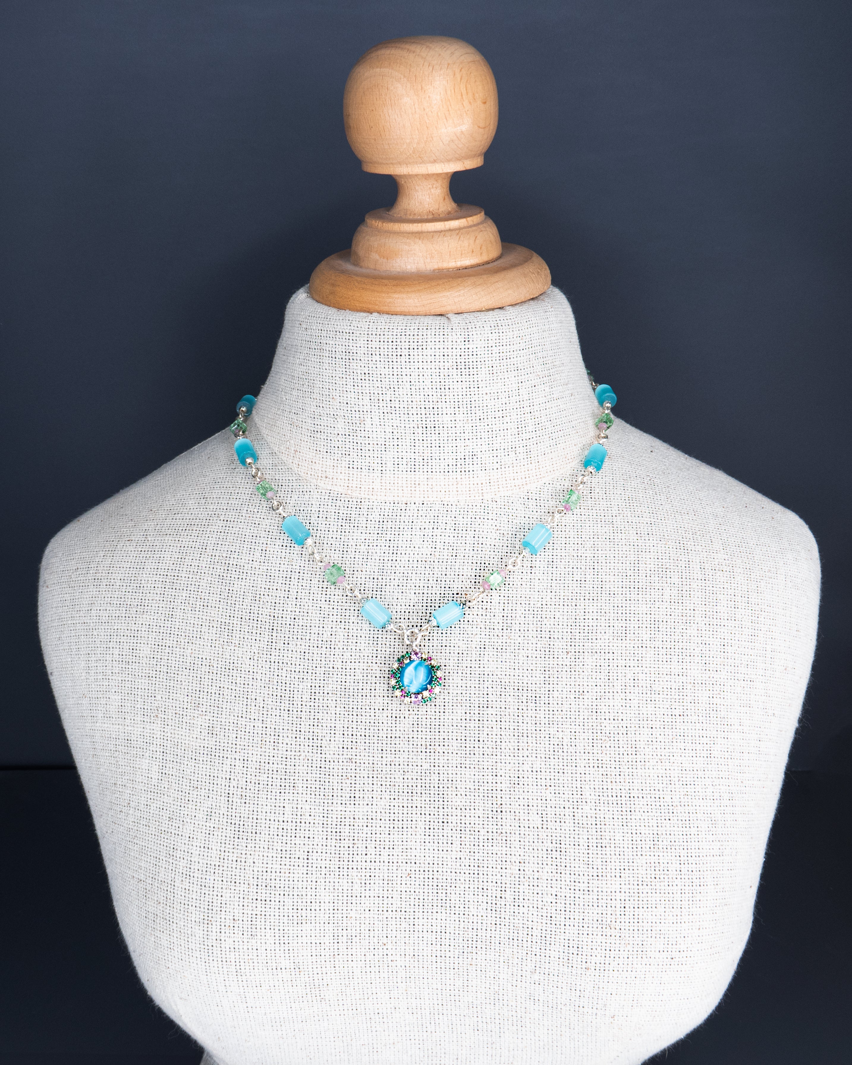 שרשרת בהירה ומרעננת, עם עיצוב טבעי ונשי – תליון פרח בגימור אלגנטי על רקע גווני תכלת שמיימיים. שילוב צבעים שמחמיא לגווני עור שונים ומאיר את הפנים באור רך ונעים.