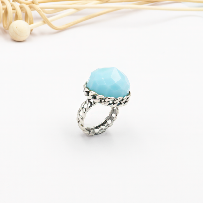 טבעת כסף בעבודת יד, כוללת באבן אופליט אובלית בגוון גוון תכלת פנינתי – צבע שמזכיר שמיים רכים או אור על פני המים. האבן מלוטשת בצורה עגולה חלקה, בעלת שקיפות פנינה קלה ואפקט זוהר פנימי שמתחלף לפי התאורה. הטבעת משדרת עידון, השראה פנימית ונוכחות שמושכת מבטים בלי להתאמץ. שילוב בין מתכת הכסף הקרה לבין הגוון התכול הרך יוצר איזון בין אסתטיקה נשית, בין אלגנטיות לאור טבעי. מתאימה לנשים שמחפשות השתקפות פנימית – רכה אך מדויקת, רגישה אך חזקה. מושלמת כמתנה עם משמעות, פריט יומיומי עם שובל של יופי, או כתכשיט לאירוע חגיגי באו