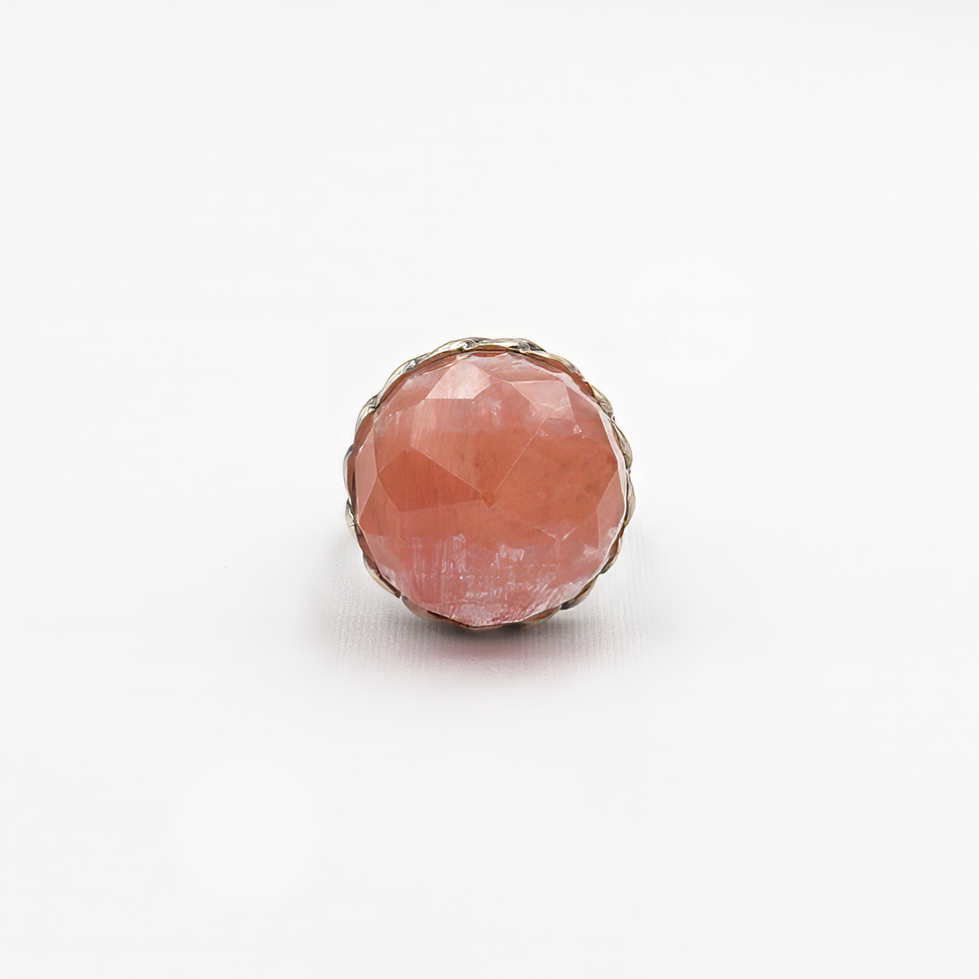טבעת כסף ייחודית מלאת תשומת לב, מעוטרת באבן גדולה בגוון ורוד־קורל עם חיתוך פאות (faceted) שמבליט את הזוהר את הברק והעומק של האבן. העיצוב משלב בסיס כסף בעבודת חריטה בדוגמה קלועה, המעניק לטבעת מראה חזק אך אלגנטי, שמזכיר טבעת שרשרת או סגנון בוהו וינטג' מתוחכם. האבן הגדולה הופכת את הטבעת לפריט נועז, כזה שלא עובר מתחת לרדאר, אך שומר על איזון אסתטי. גוון האבן מחמיא לעור, מתאים לקיץ ולחורף כאחד, ויוצר ניגוד יפהפה עם גוון המתכת. תכשיט מיוחד שמדגיש אישיות, טעם ייחודי ואמירה אישית לא שגרתית. מושלמת כטבעת מתנה, ליום־י