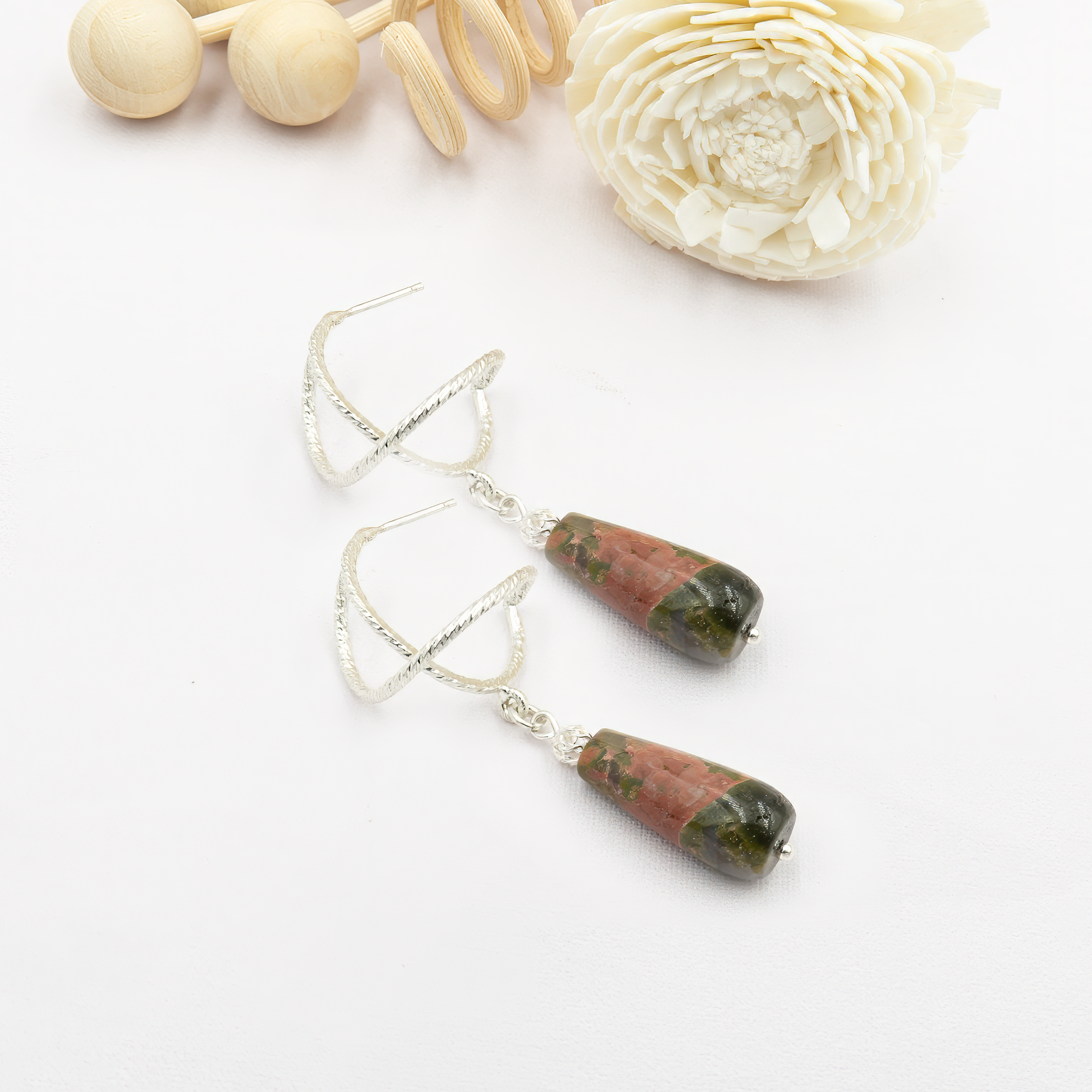 עגילי כסף מעוצבים עם אבן יוניקייט טבעית – תכשיט בעל מראה ייחודי, צבעוניות חמה ואופי עמוק. היוניקייט ידועה כאבן של איזון רגשי, ריפוי פנימי וחיבור בין לב לקרקע. הגוונים המשלבים ירוק וורוד יוצרים ניגוד הרמוני ומקורי, שמתאים במיוחד לנשים שמחפשות תכשיט עם משמעות וסטייל לא שגרתי. עגילים קלילים, נוחים, ויפים ליום ולערב כאחד.

