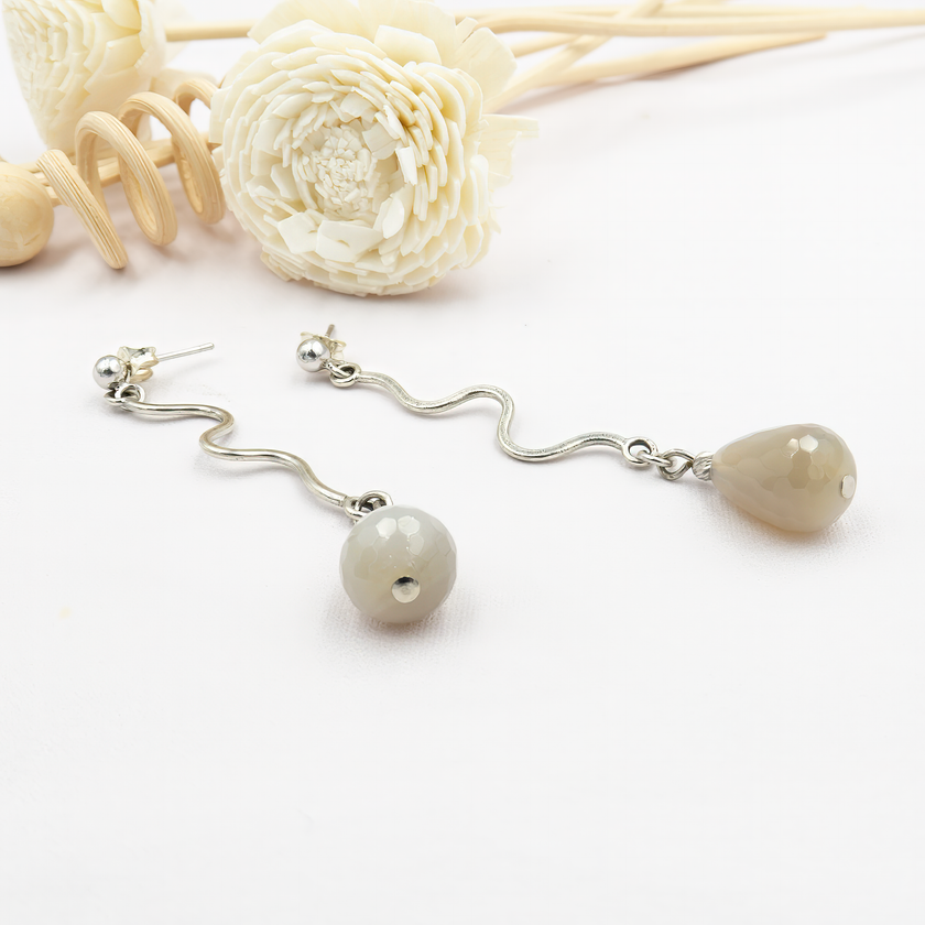 עגילי כסף ארוכים עם אבן אגת בגוון אפור טבעי – עגילים קלילים ואלגנטיים שמתאימים לכל מראה. האגת האפורה משתלבת בהרמוניה עם גימור הכסף ויוצרת מראה מודרני, רגוע ומאוזן. מבנה העגיל מדגיש את קו הלסת ומוסיף תנועה עדינה, כזו שלא גונבת את ההצגה אך לא נעלמת. תכשיט על-זמני שמתאים לנשים שאוהבות שיק מעודן ולא מתאמץ.

