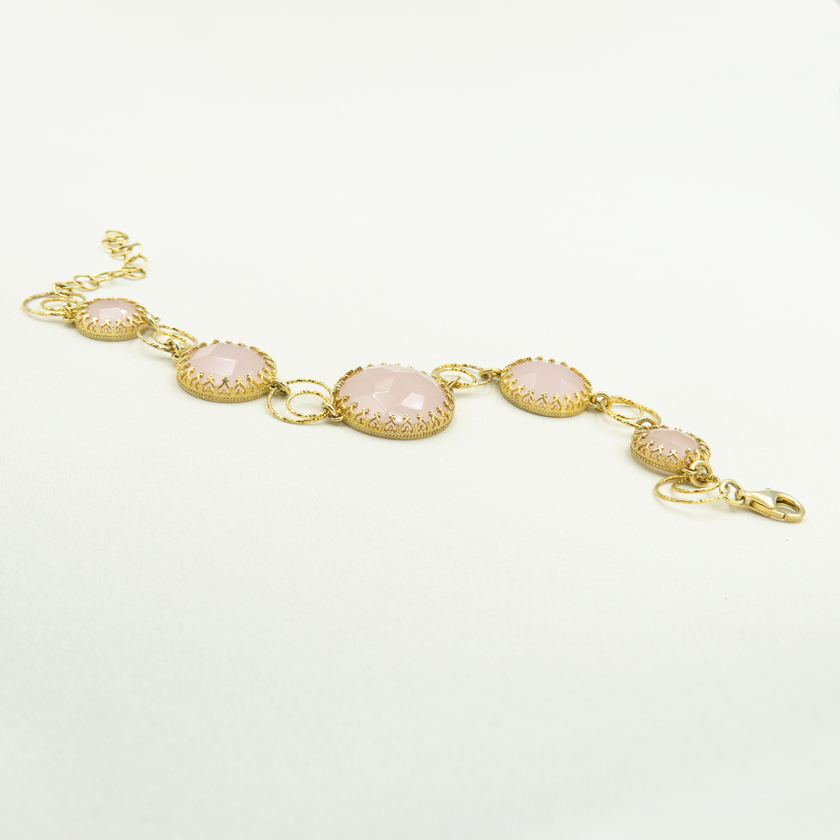 צמיד מעוצב בעבודת יד, עשוי כסף בציפוי זהב ומשובץ באבני אופליט ורוד בגימור מלוטש ופאות נוצצות. כל אבן משובצת במסגרת זהב עם פרטים עדינים, המחברים את האלמנטים בעיצוב סימטרי ואלגנטי. הגוון הוורוד הרך של האופליט מעניק תחושת שלווה ואהבה עצמית. מתאים לנשים שמחפשות תכשיט עם מראה קלאסי ורומנטי, שניתן לענוד לבד או כשילוב מושלם עם שרשרת תואמת.

