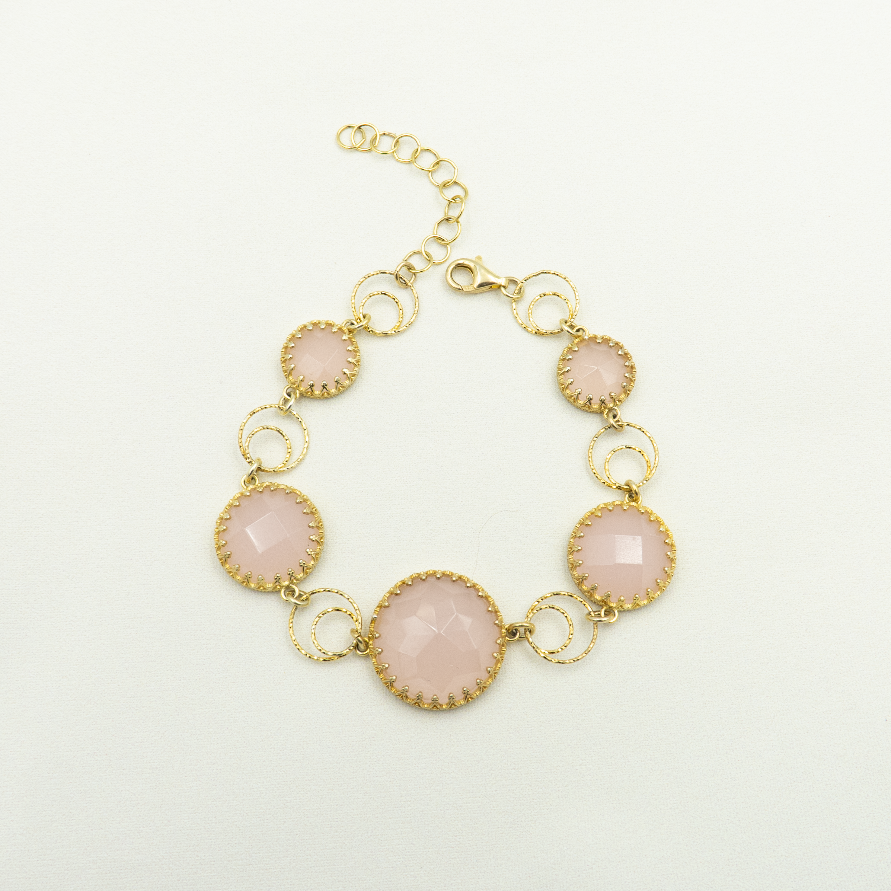 צמיד כסף מצופה זהב עם אבני אופליט ורוד בגימור פאות מנצנץ, בעיצוב עגול ורומנטי. כל אבן משובצת במסגרת עדינה בעלת טקסטורה דמוית תחרה, המקנה לתכשיט מראה נשי, מעודן ומלא נוכחות. הצמיד כולל חוליות עגולות שנותנות לו תנועה טבעית ותחושת קלילות על פרק כף היד. מושלם כליווי לשמלת ערב, חתונה או אירוע חגיגי. תכשיט שמשדר אלגנטיות רכה עם נגיעה מלכותית.

