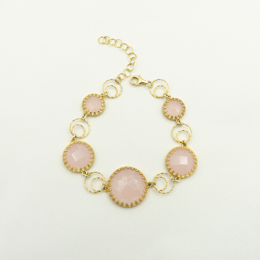 צמיד כסף מצופה זהב עם אבני אופליט ורוד בגימור פאות מנצנץ, בעיצוב עגול ורומנטי. כל אבן משובצת במסגרת עדינה בעלת טקסטורה דמוית תחרה, המקנה לתכשיט מראה נשי, מעודן ומלא נוכחות. הצמיד כולל חוליות עגולות שנותנות לו תנועה טבעית ותחושת קלילות על פרק כף היד. מושלם כליווי לשמלת ערב, חתונה או אירוע חגיגי. תכשיט שמשדר אלגנטיות רכה עם נגיעה מלכותית.

