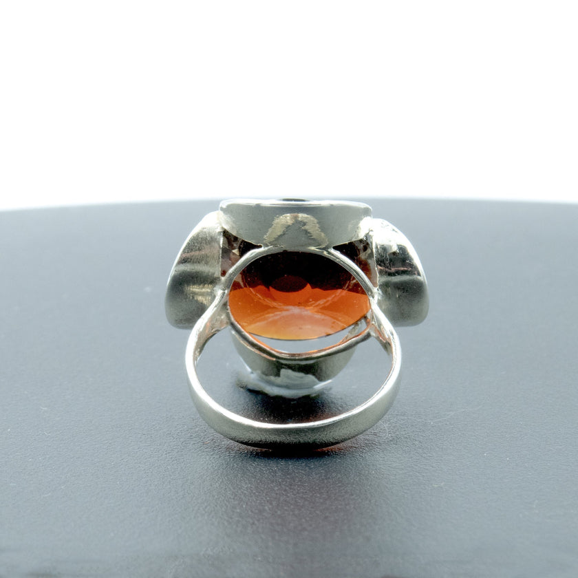 טבעת כסף מעוצבת בעבודת יד, מעוטרת בקריסטל בגוון בורדו המדמה את אבן הגארנט – צבע יין עשיר עם עומק רגשי וניצוץ עמוק. האבן מלוטשת בפאות רבות, מה שמעניק לה נצנוץ פנימי וזוהר משתנה בהתאם לזוויות האור. העיצוב של הטבעת שומר על איזון בין סגנון נצחי לבין אופי בולט, ומתאים לנשים שמבקשות תכשיט עם משמעות, עומק וסגנון אישי. צבע האבן משתלב נהדר עם גוון המתכת הכסופה, ויוצר מראה חם, נשי ועוצמתי. הטבעת מתאימה גם כפריט יום־יומי יוקרתי וגם כתוספת מרשימה למראה ערב – רעיון מתנה מרגש כמתנה רומנטית או כאמירה אישית.