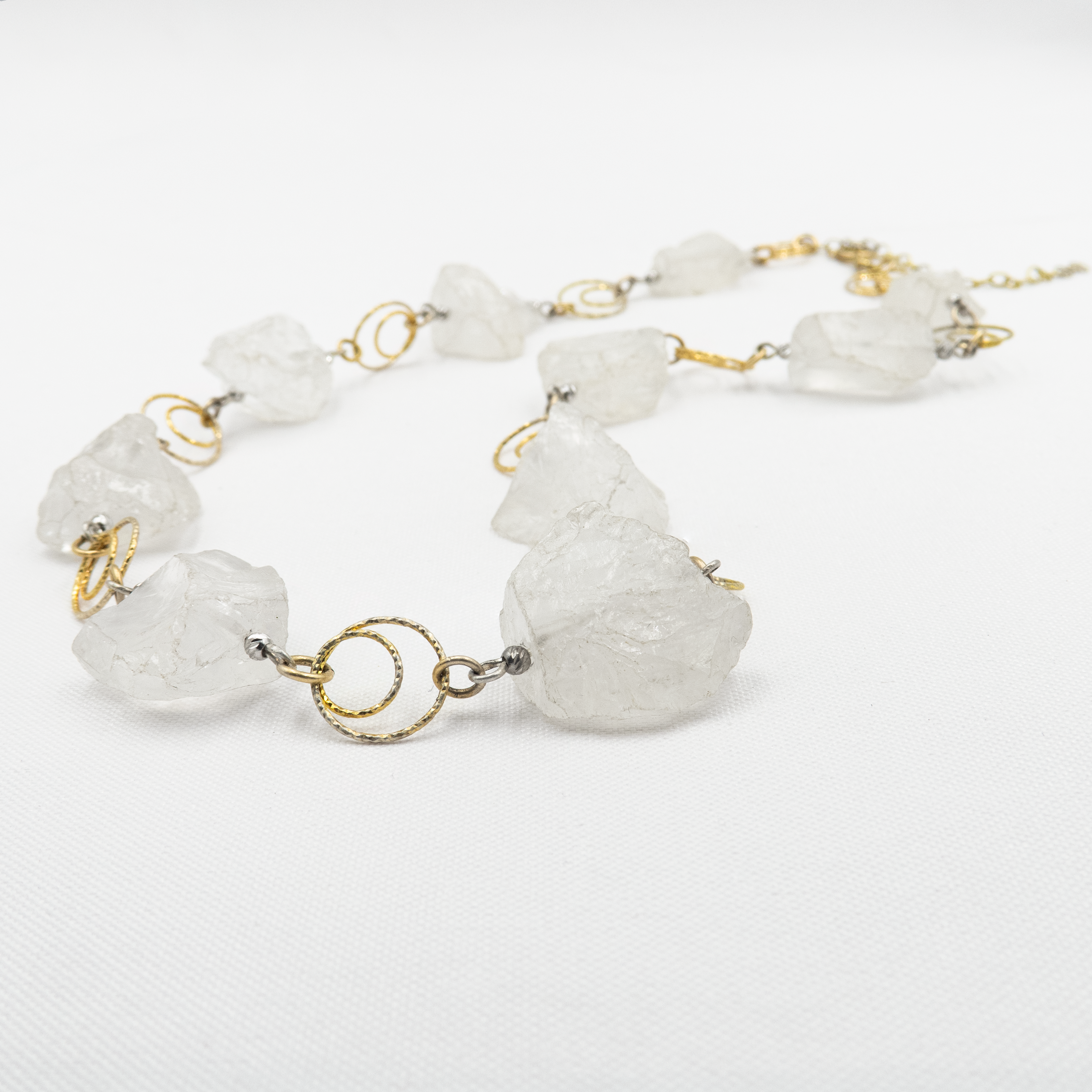שרשרת כסף בציפוי זהב, בעבודת יד, עם קוורץ לבן בגימור חלק – תכשיט קלאסי עם מראה טהור, עדין ואלגנטי. הקוורץ הלבן מעניק תחושת רוגע פנימית, ומקרין אור רך שמתאים לכל גוון עור ולכל סגנון לבוש. ההזהב מוסיף טאץ' של אלגנטיות מודרנית, ומשלים את הנוכחות של האבן בגימור מודרני ועדין. תכשיט מושלם למי שאוהבת שילוב של פשטות וסטייל, של ניקיון עיצובי עם נגיעה של זהר. מתאים ליום או ערב, לאירועים או ללבוש יומיומי – מעודן, קלאסי ונשאר תמיד באופנה.