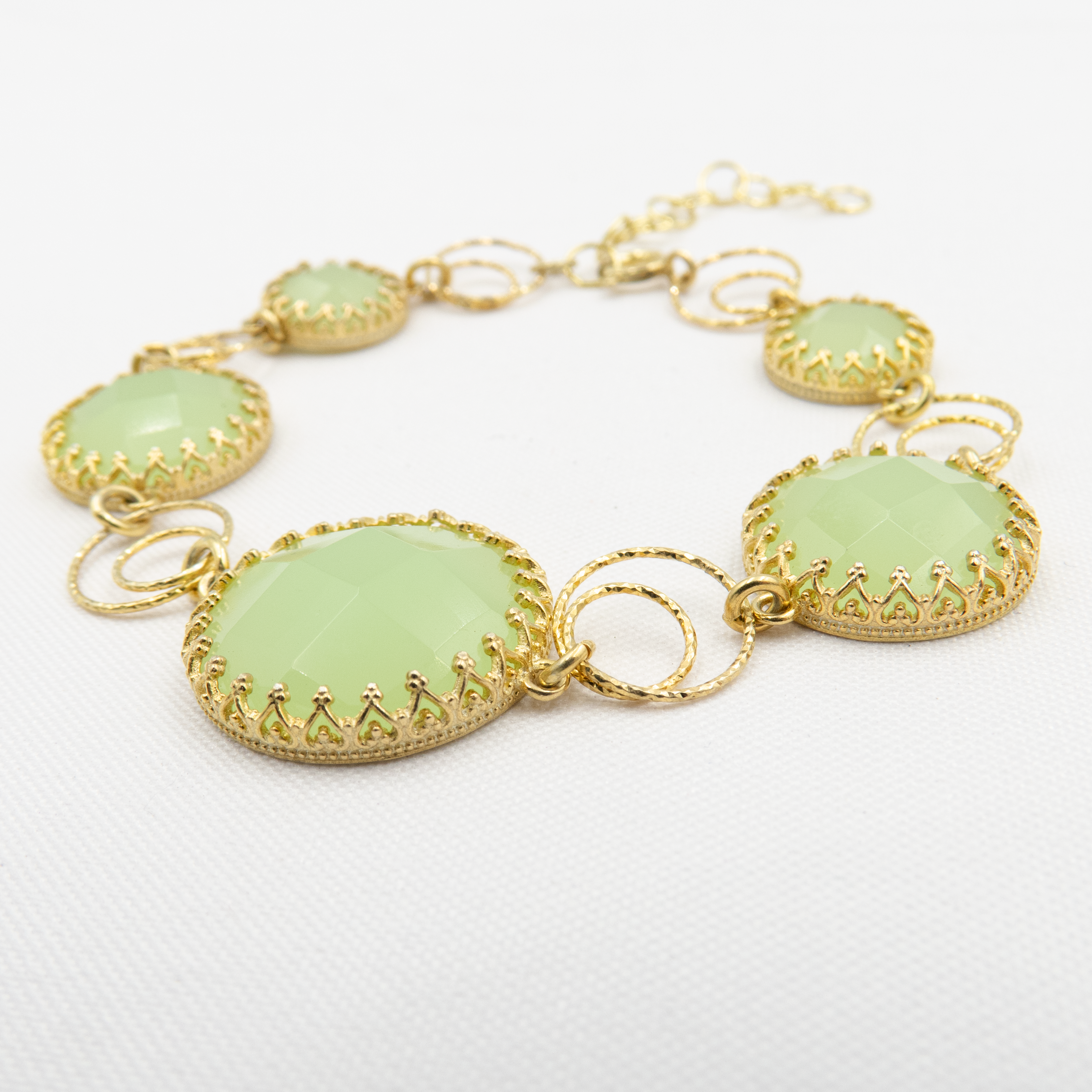 צמיד ייחודי בעבודת יד, משובץ ברצף של אבני אופליט ירוקות בגוונים משתנים – מפיסטוק עד טורקיז רך, עם ברק פנימי חלבי המאפיין את האבן. כל אבן משובצת במסגרת כסף או בציפוי זהב, ומחוברת בחוליות עדינות שמאפשרות תנועה טבעית סביב פרק כף היד. הצמיד יוצר מראה עשיר של 