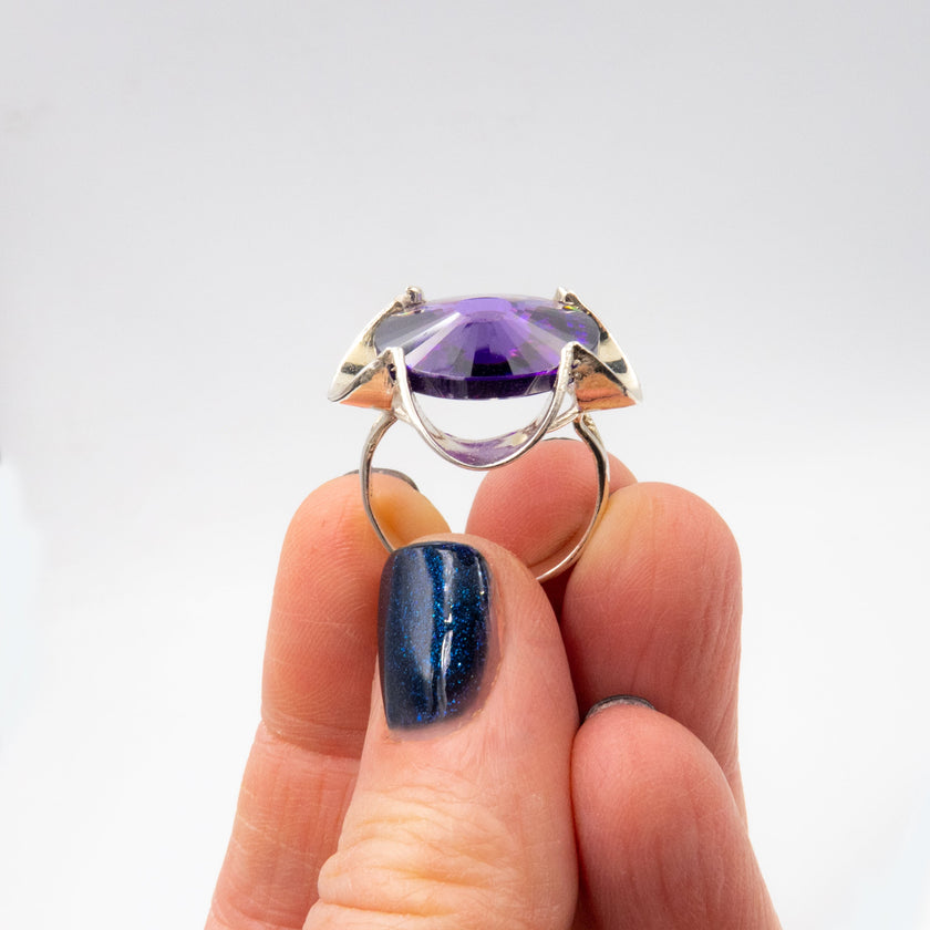 טבעת כסף בעבודת יד, כוללת בקריסטל סגול בגוון המזכיר את אבן האמטיסט – אור סגול רגשי שנע בין לבנדר עדין לסגול כהה. האבן חתוכה בפאות מדויקות ויוצרת משחקי אור שמעניקים לה זוהר פנימי שקט. השילוב בין גוון האבן האצילי לבין מתכת הכסף המלוטשת מעניק לטבעת חיבור בין חוזק לעדינות, בין קלאסיקה לאנרגיה מודרנית. התכשיט מתאים לנשים שמחפשות עומק, הבעה אישית ומיוחדת שאינה מובנת מאליה. קריסטל בגוון אמטיסט מסמל חיבור רגשי עמוק – ומתאים כתוספת למראה יומיומי מלא חן או כתכשיט עם משמעות לערב מיוחד.