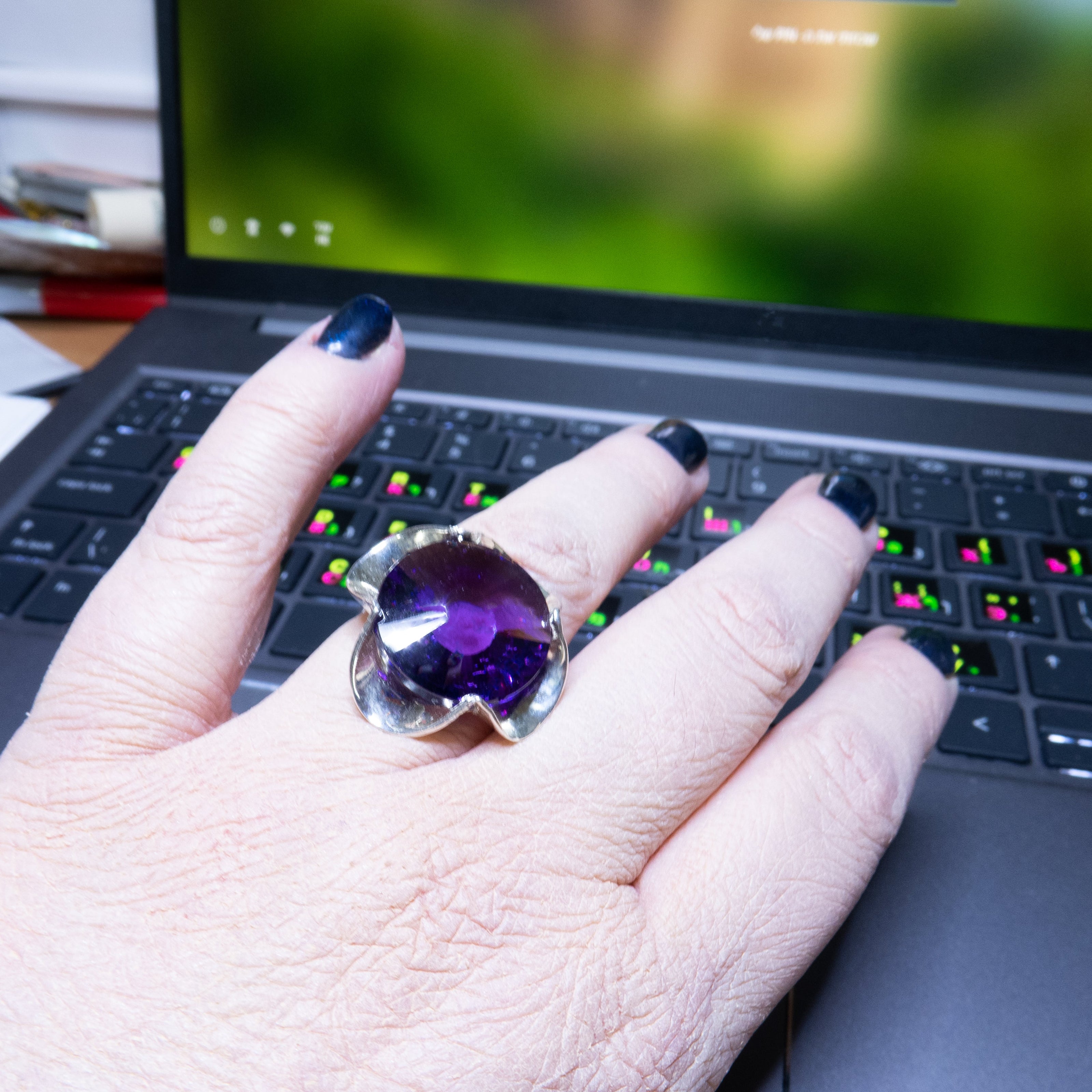 טבעת כסף בעבודת יד, מעוטרת בקריסטל סגול בגוון המזכיר את אבן האמטיסט – סגול מלכותי שנע בין לבנדר עדין לסגול כהה. האבן חתוכה בפאות מדויקות ויוצרת משחקי אור שמעניקים לה אור רך ומרגש. השילוב בין גוון האבן האצילי לבין מתכת הכסף המלוטשת מעניק לטבעת שילוב של רגש ואלגנטיות, בין קלאסיקה לאנרגיה מודרנית. התכשיט מתאים לנשים שמחפשות עומק, אופי רגשי עמוק שאינה מובנת מאליה. קריסטל בגוון אמטיסט מסמל חיבור רגשי עמוק – ומתאים כתוספת למראה יומיומי מלא חן או כתכשיט עם משמעות לערב מיוחד.
